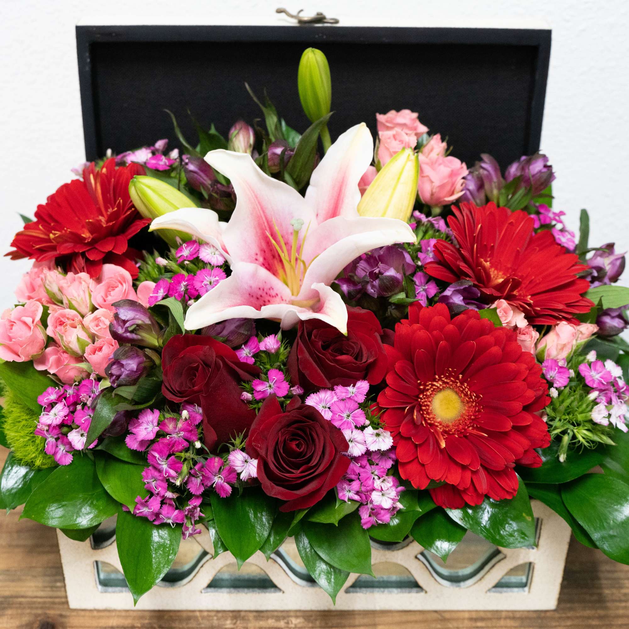 Mixed bouquet with lilies, roses, and red gerbera daisies in a rectangular box
