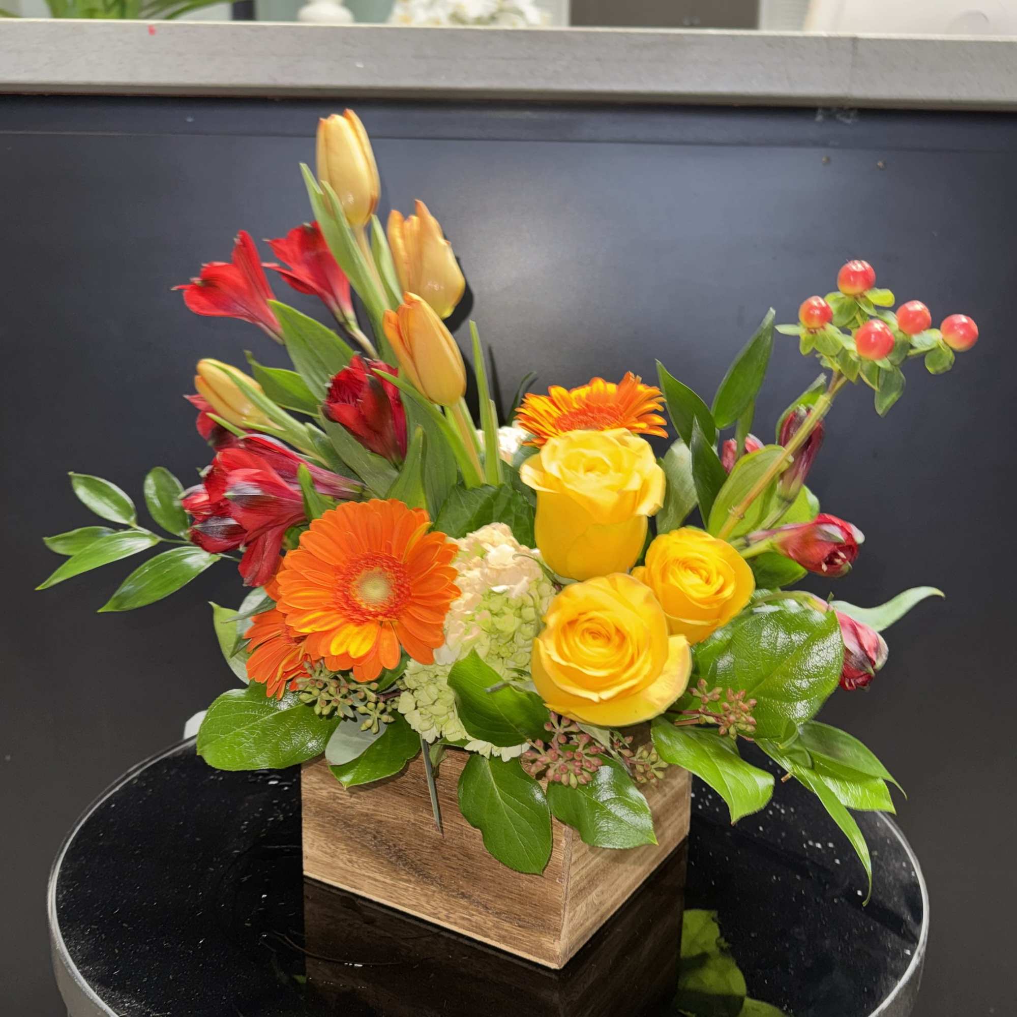 Mixed bouquet of yellow roses, orange gerberas, and red alstroemeria in a wooden box