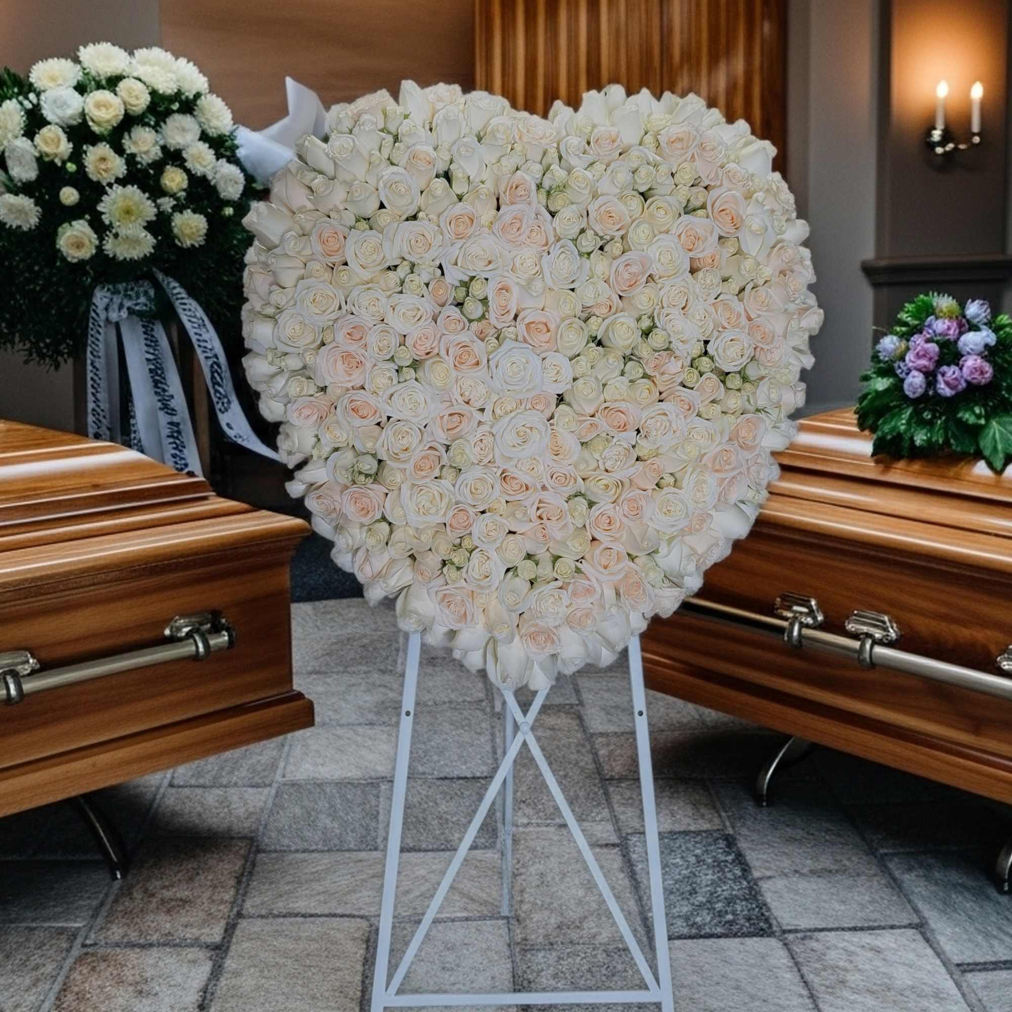 Heart-shaped white rose funeral spray on a stand