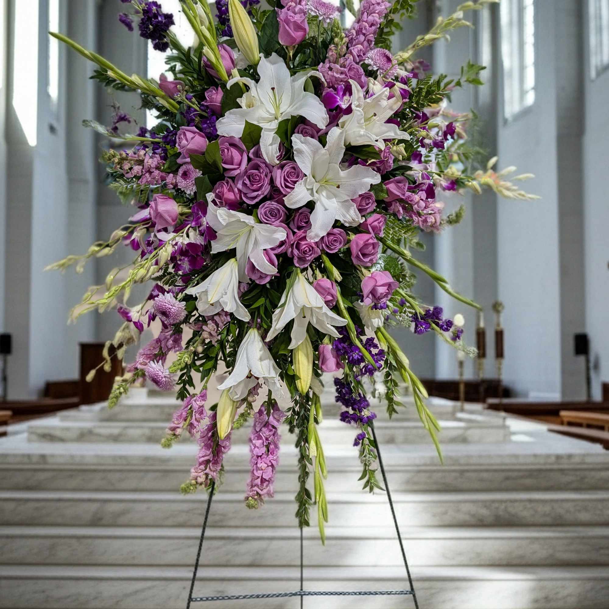 Large purple and white floral standing arrangement on an easel