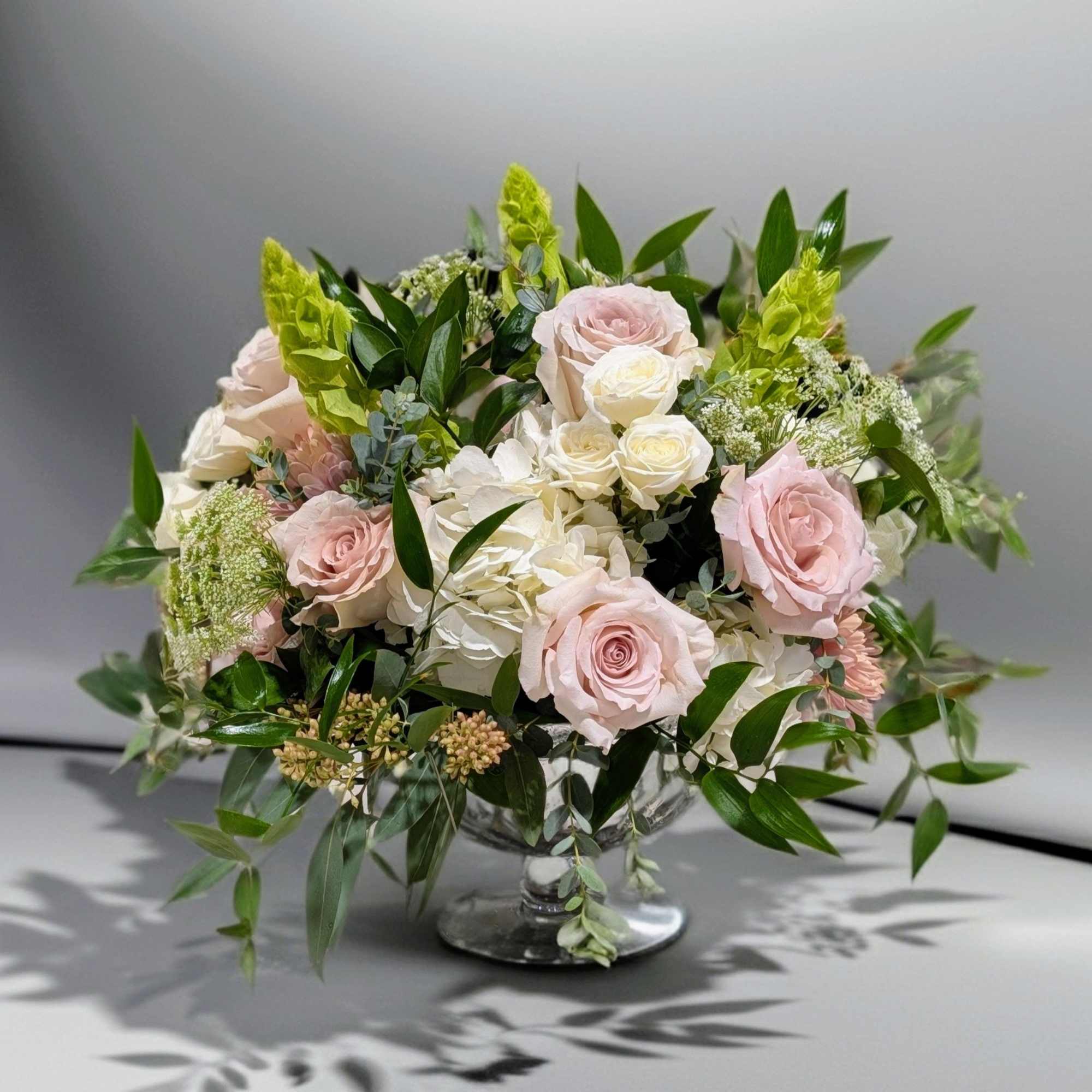 Soft color hues of seasonal flowers design in a mercury glass compote, photo 2 of 3