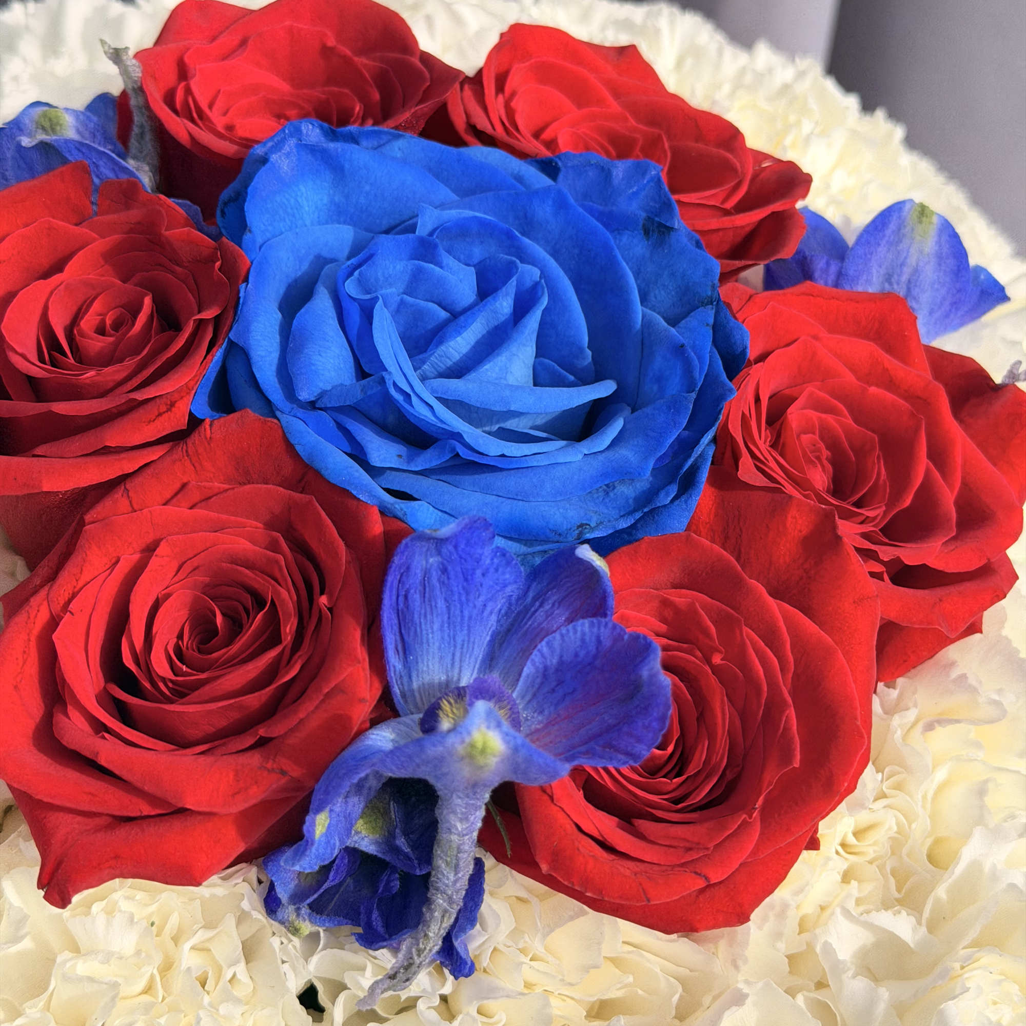 Red and blue roses arranged with white flowers in a bouquet