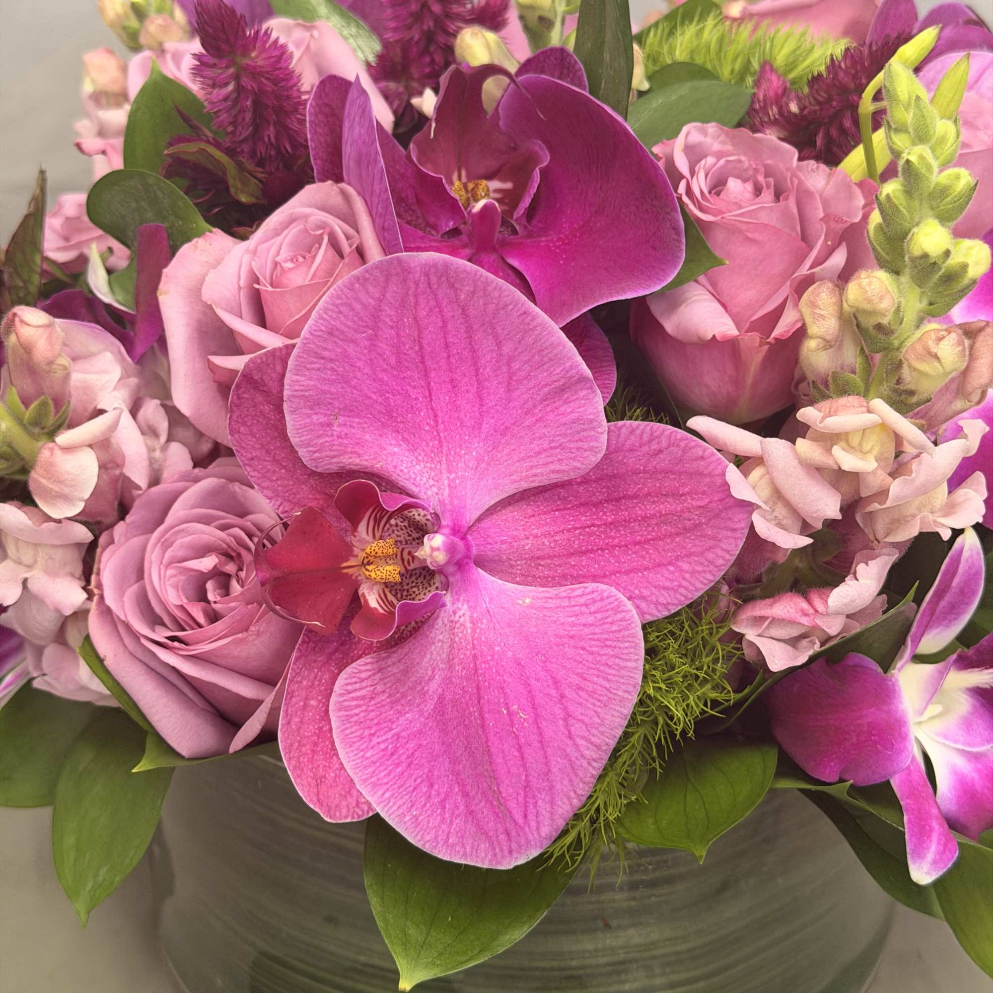 Pink orchid and rose bouquet in a clear glass vase