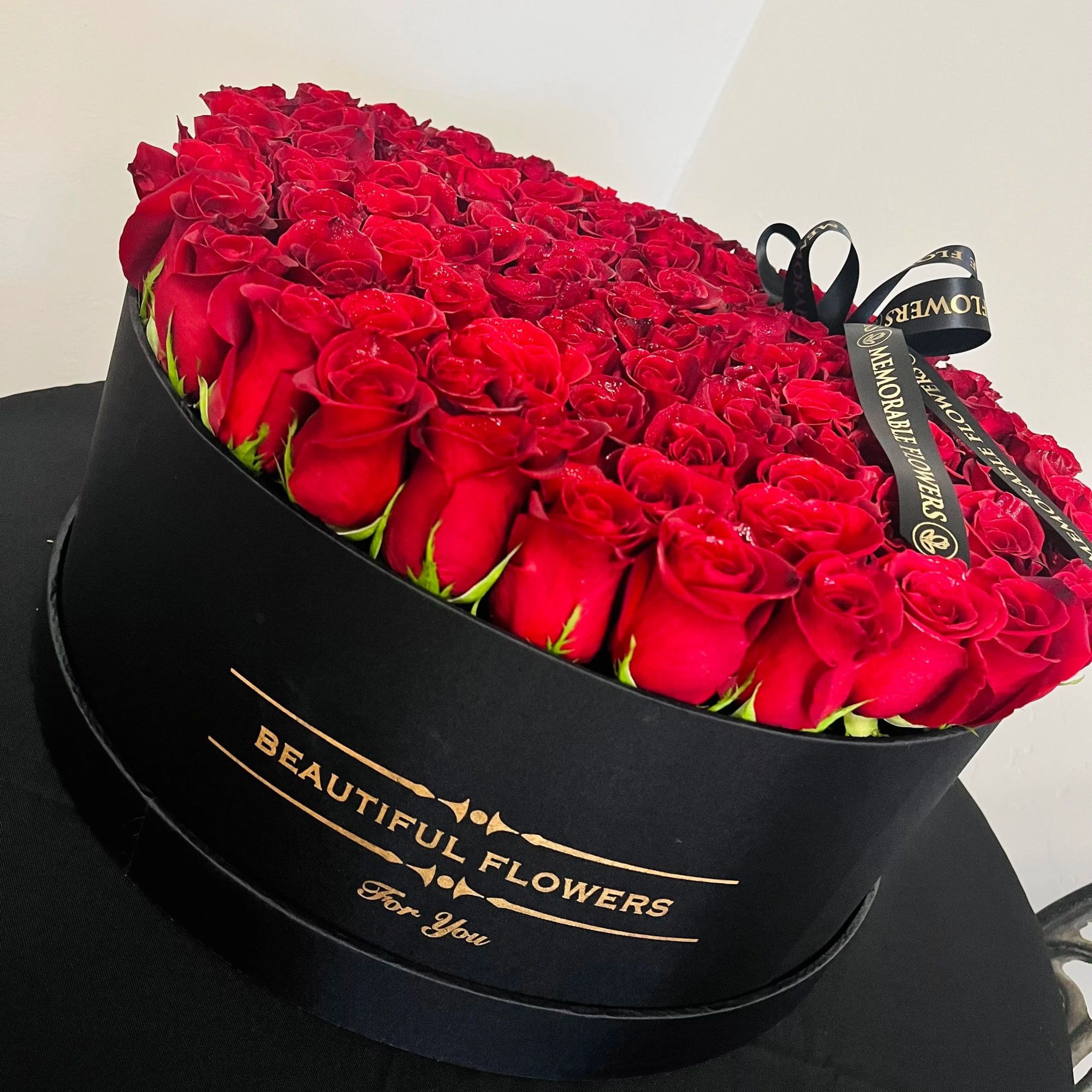 Heart-shaped box filled with red roses and a black ribbon bow