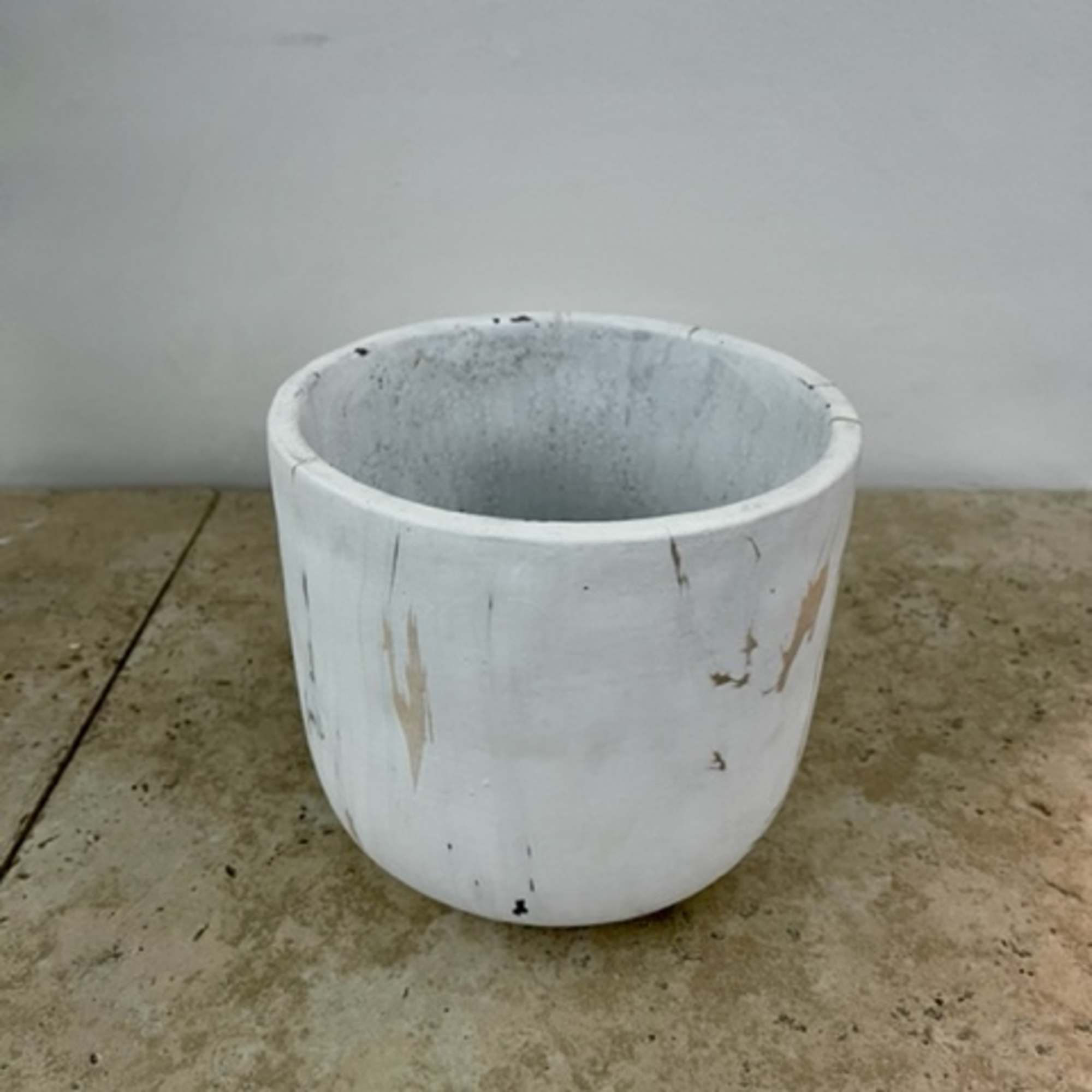 White ceramic planter pot on a concrete floor