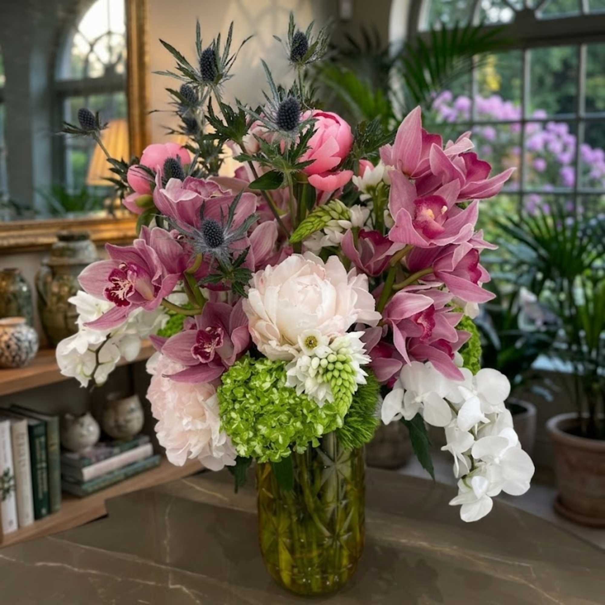 Pink and white orchid arrangement in a glass vase with green hydrangea