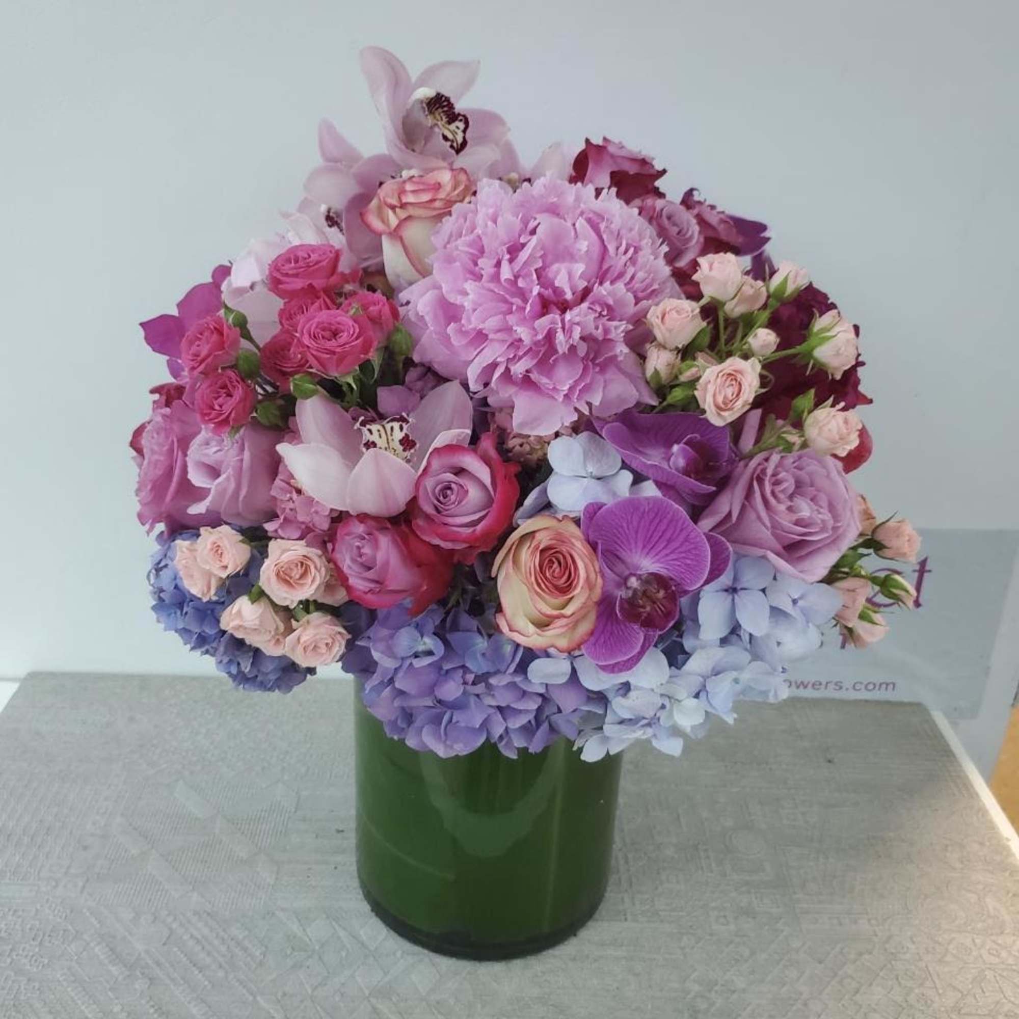 Pink and purple mixed flower arrangement in a green vase