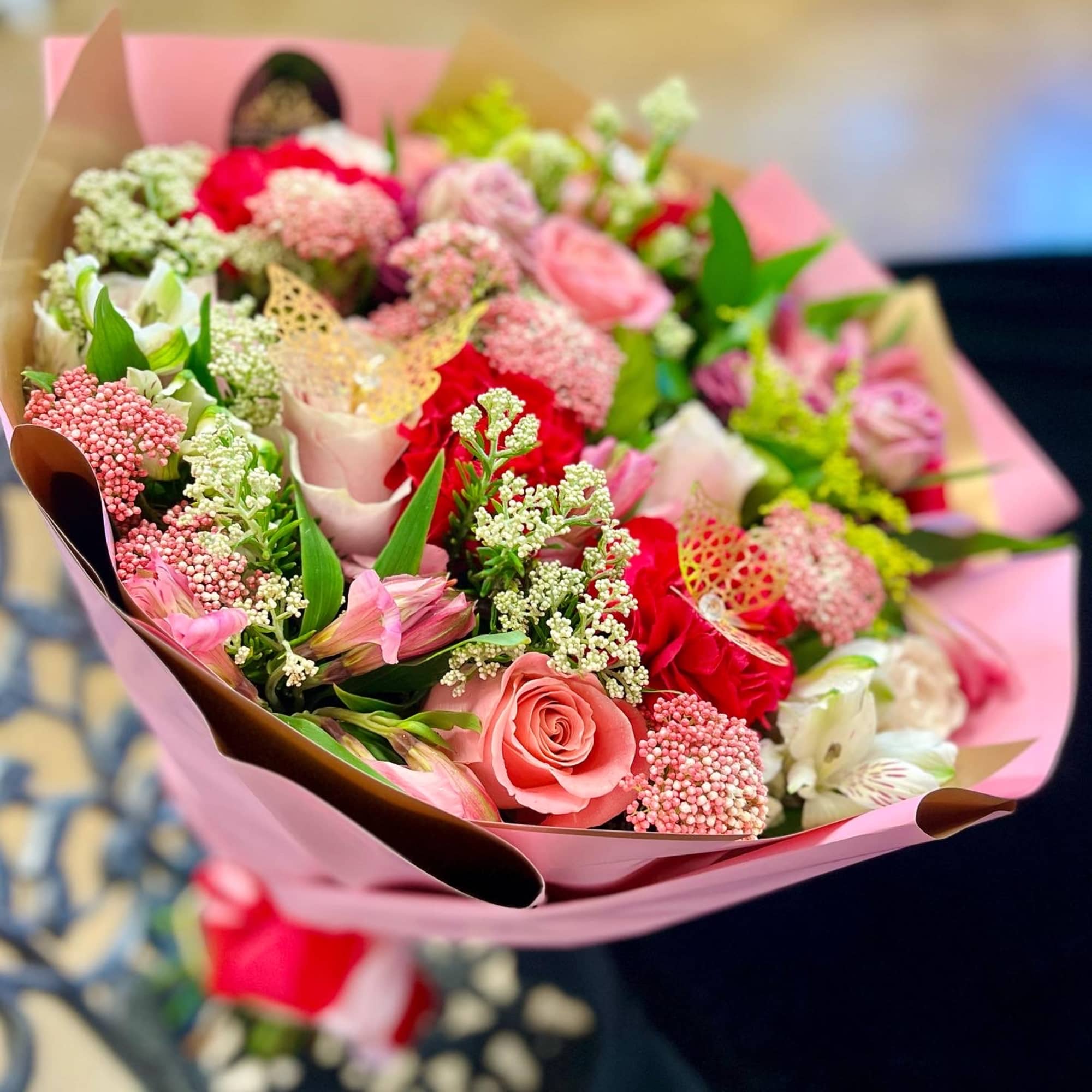 Pink mixed bouquet with roses and small filler flowers wrapped in paper
