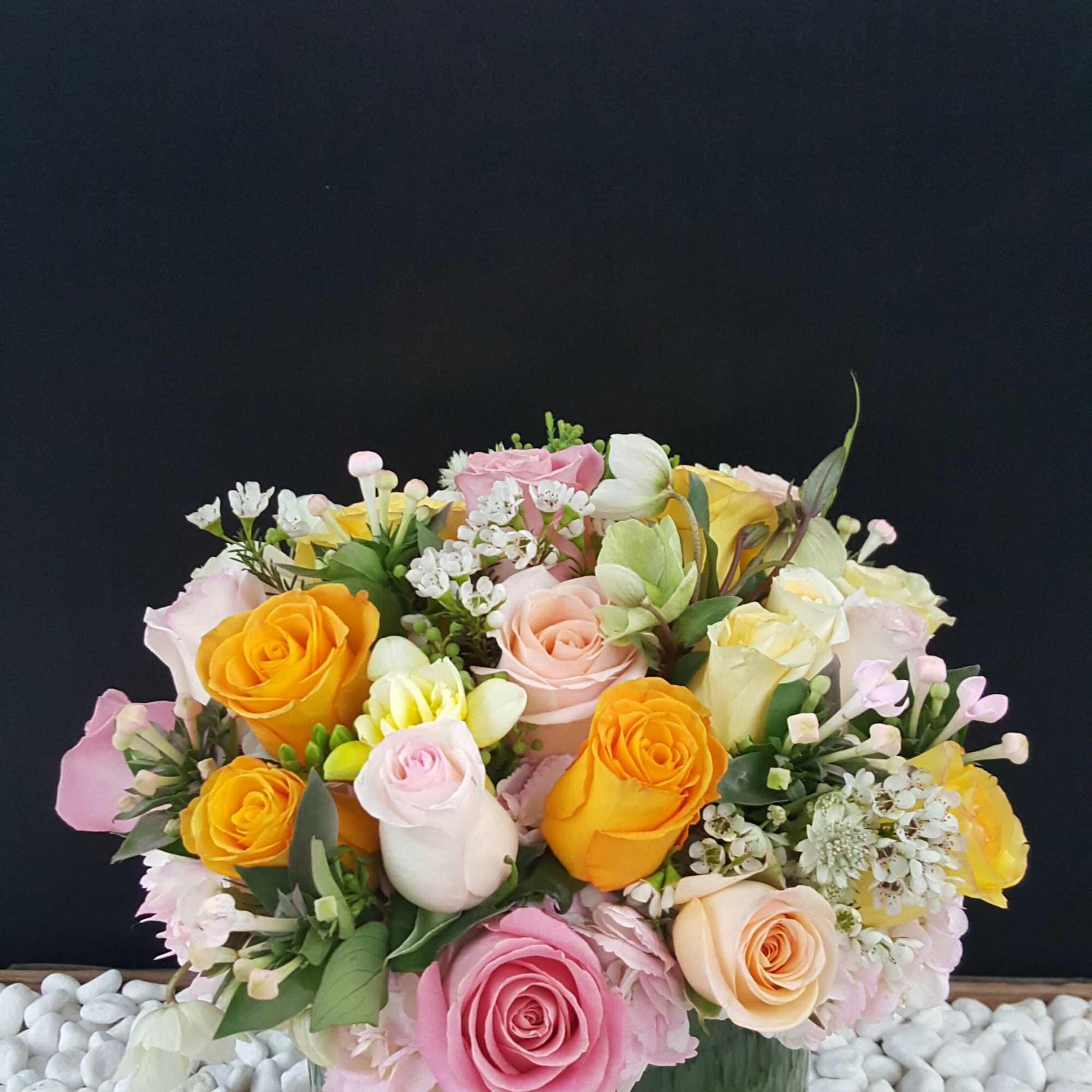 Mixed pastel roses arranged in a green glass vase