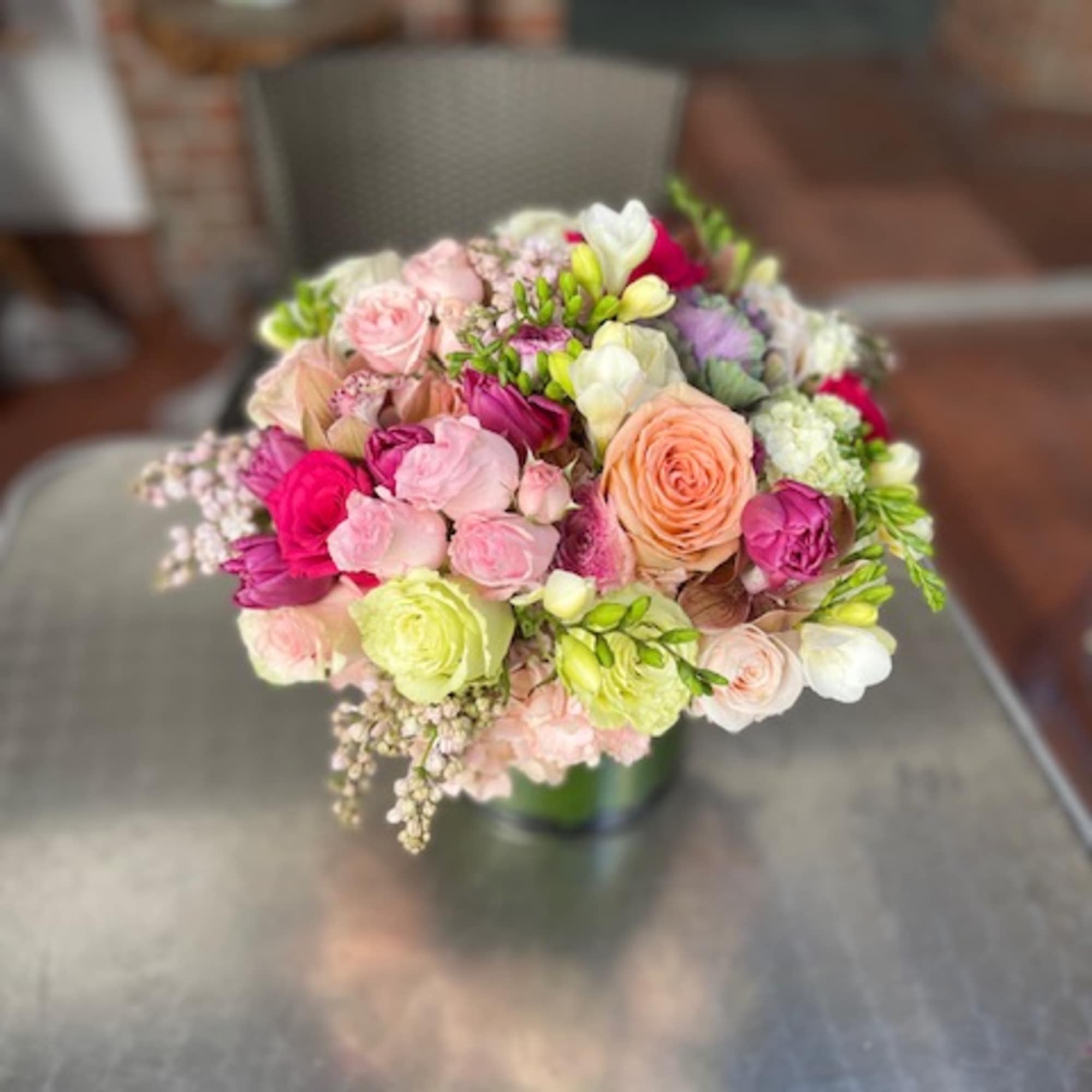 Mixed bouquet of pink, peach, white, and lime flowers in a vase