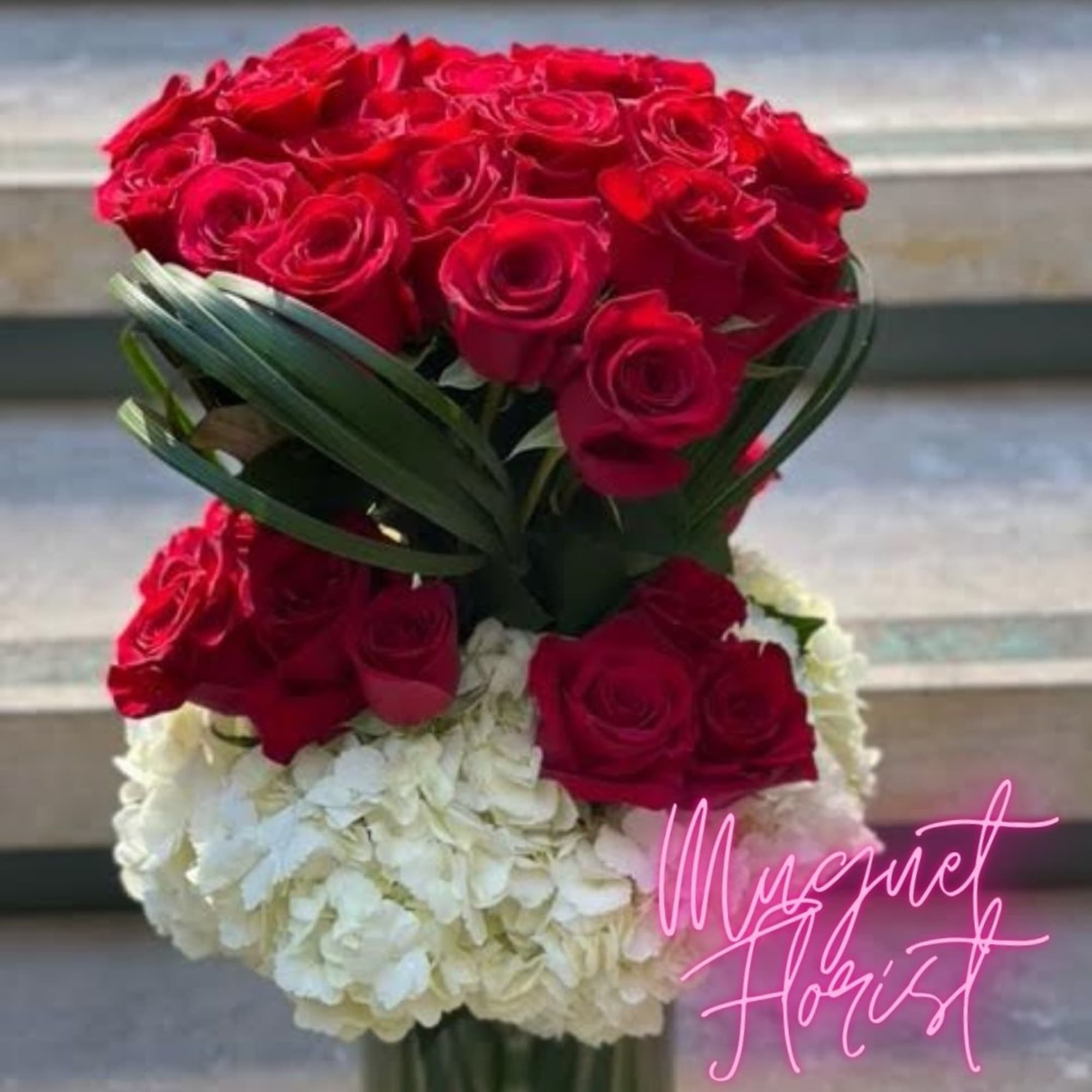Red roses arranged above white hydrangeas in a tall bouquet