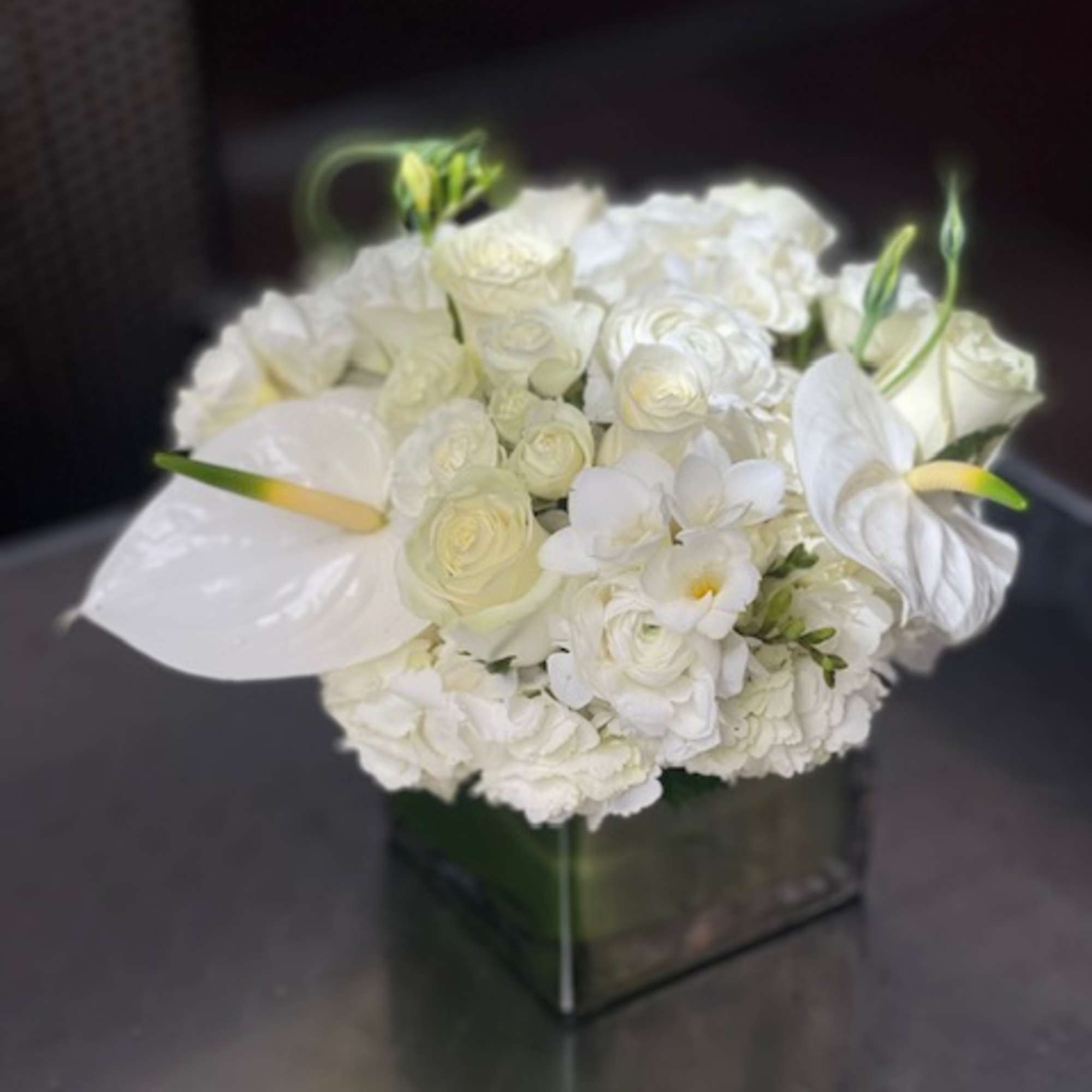 White floral arrangement with roses and calla lilies in a square vase