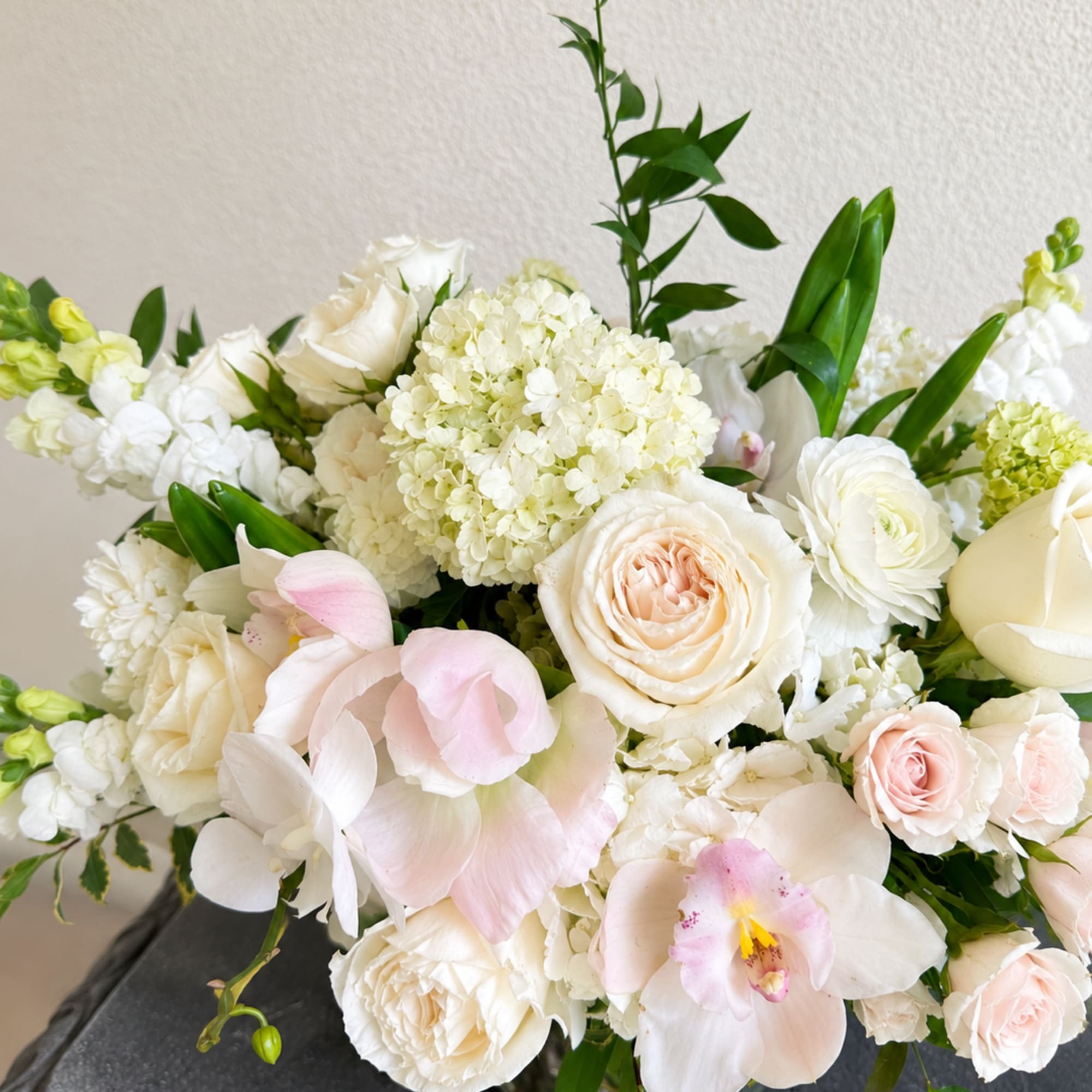 White and blush floral arrangement with roses, hydrangeas, and orchids