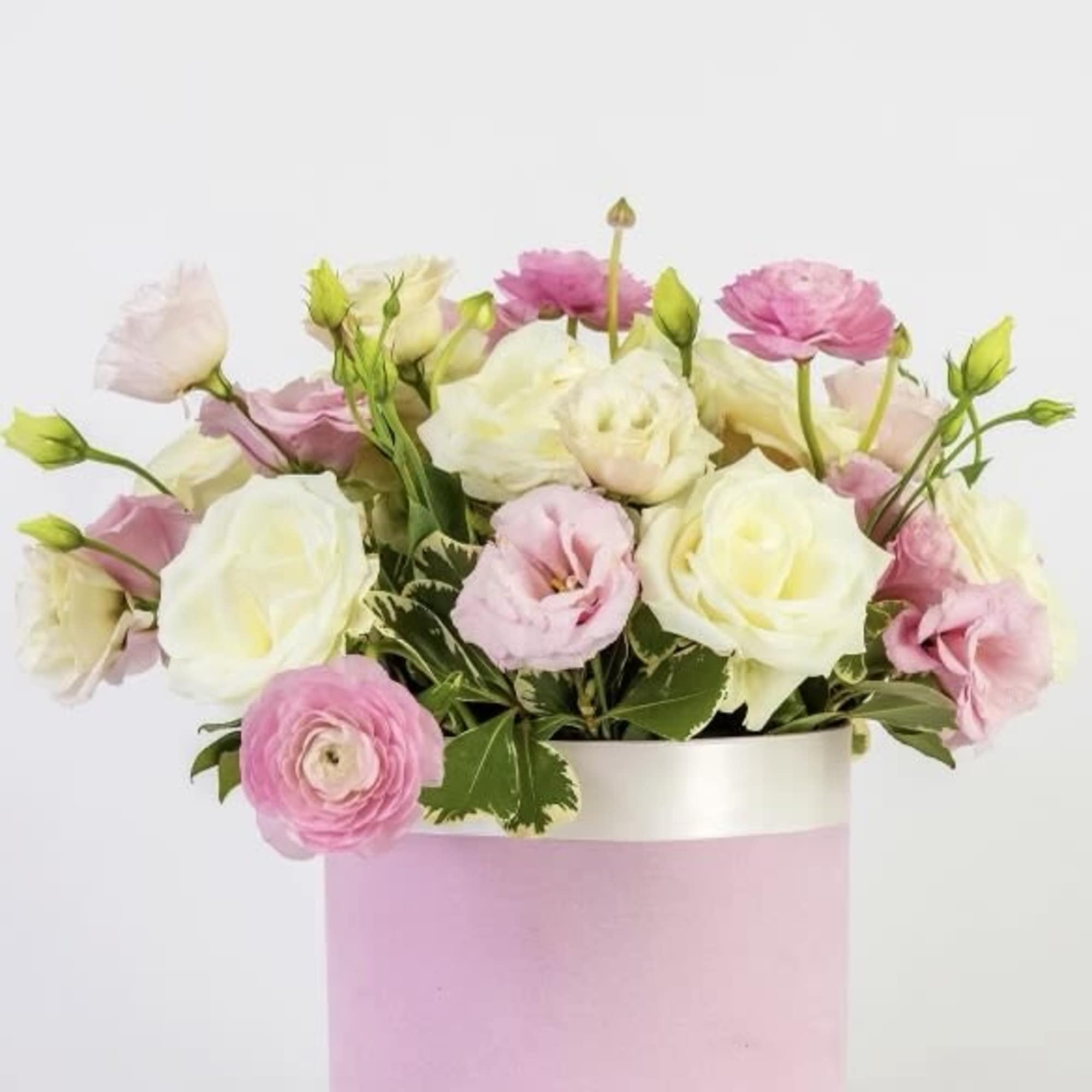 Pink and white flowers arranged in a pastel pink box