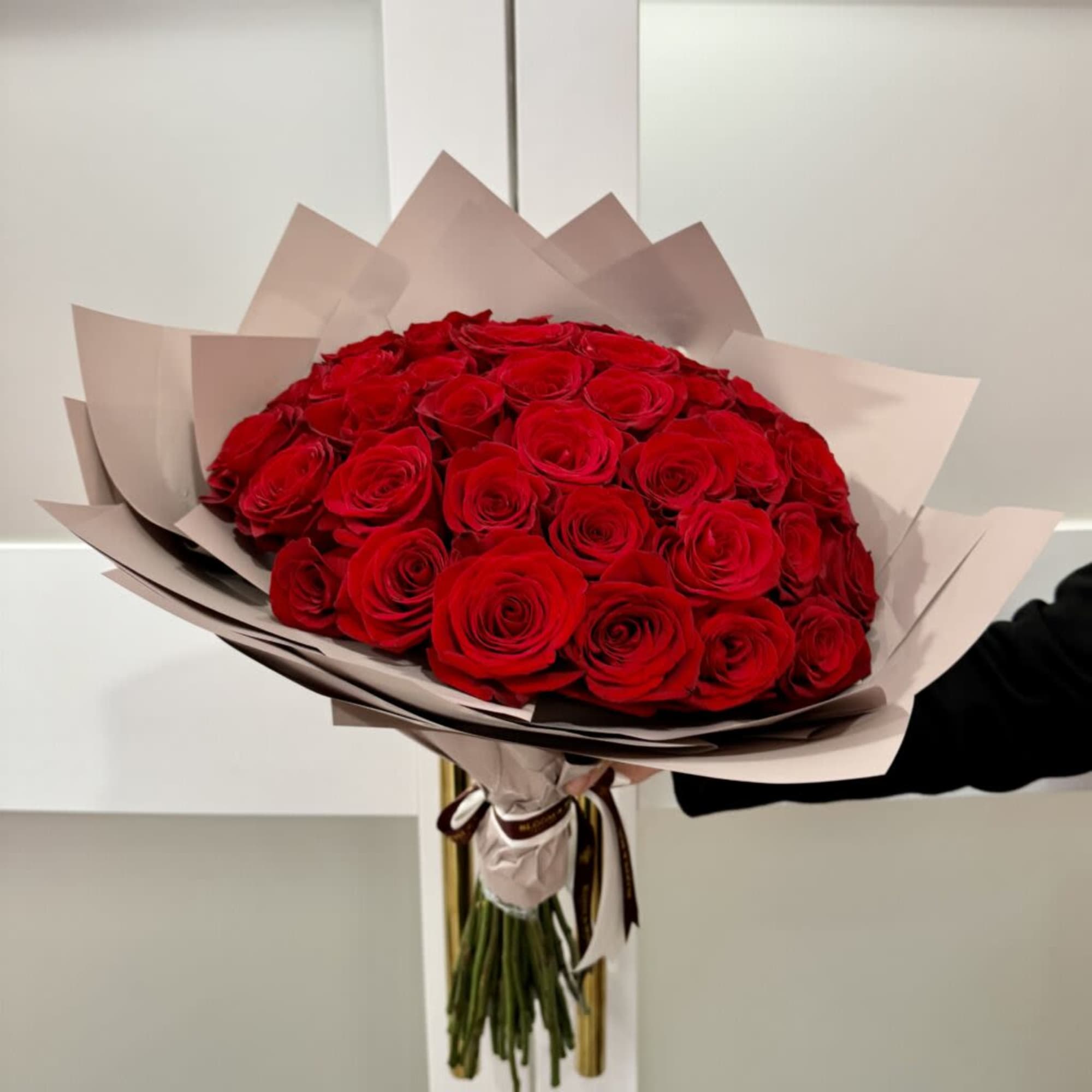 Large bouquet of red roses wrapped in pale paper