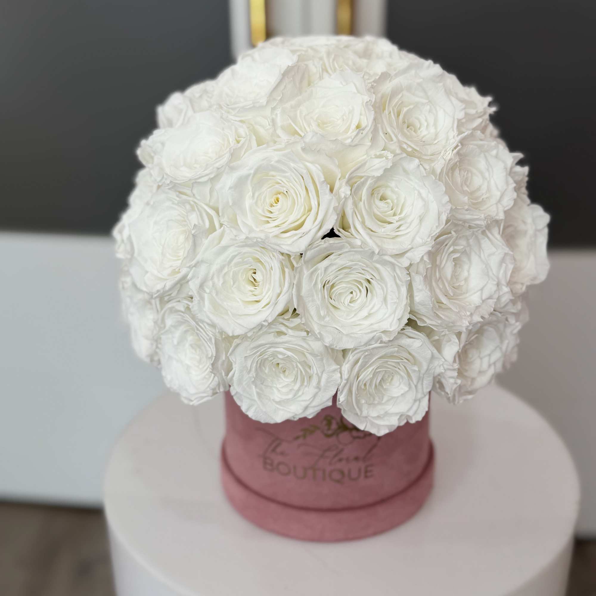 Round bouquet of white roses in a pink box