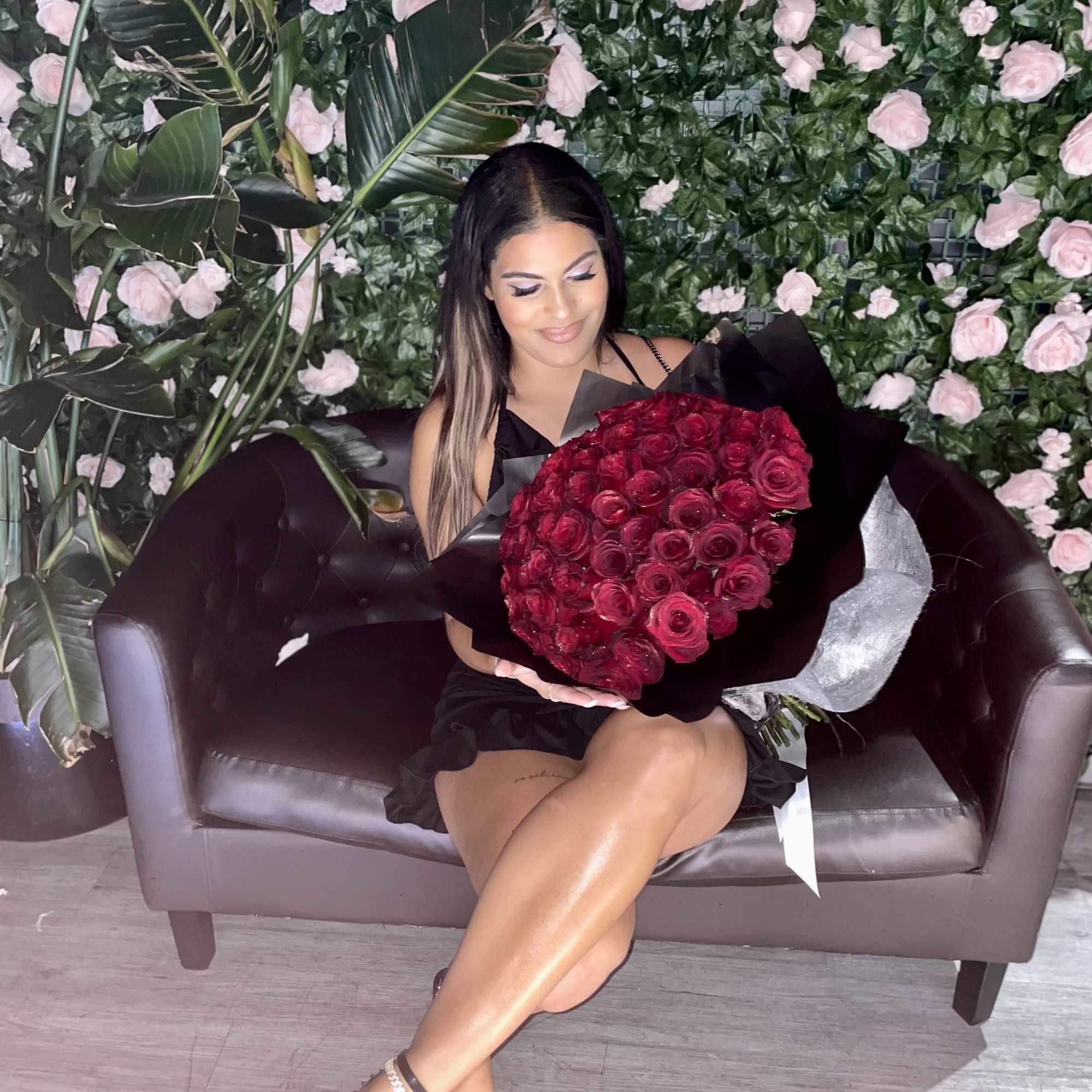 Woman holding a large bouquet of red roses on a sofa