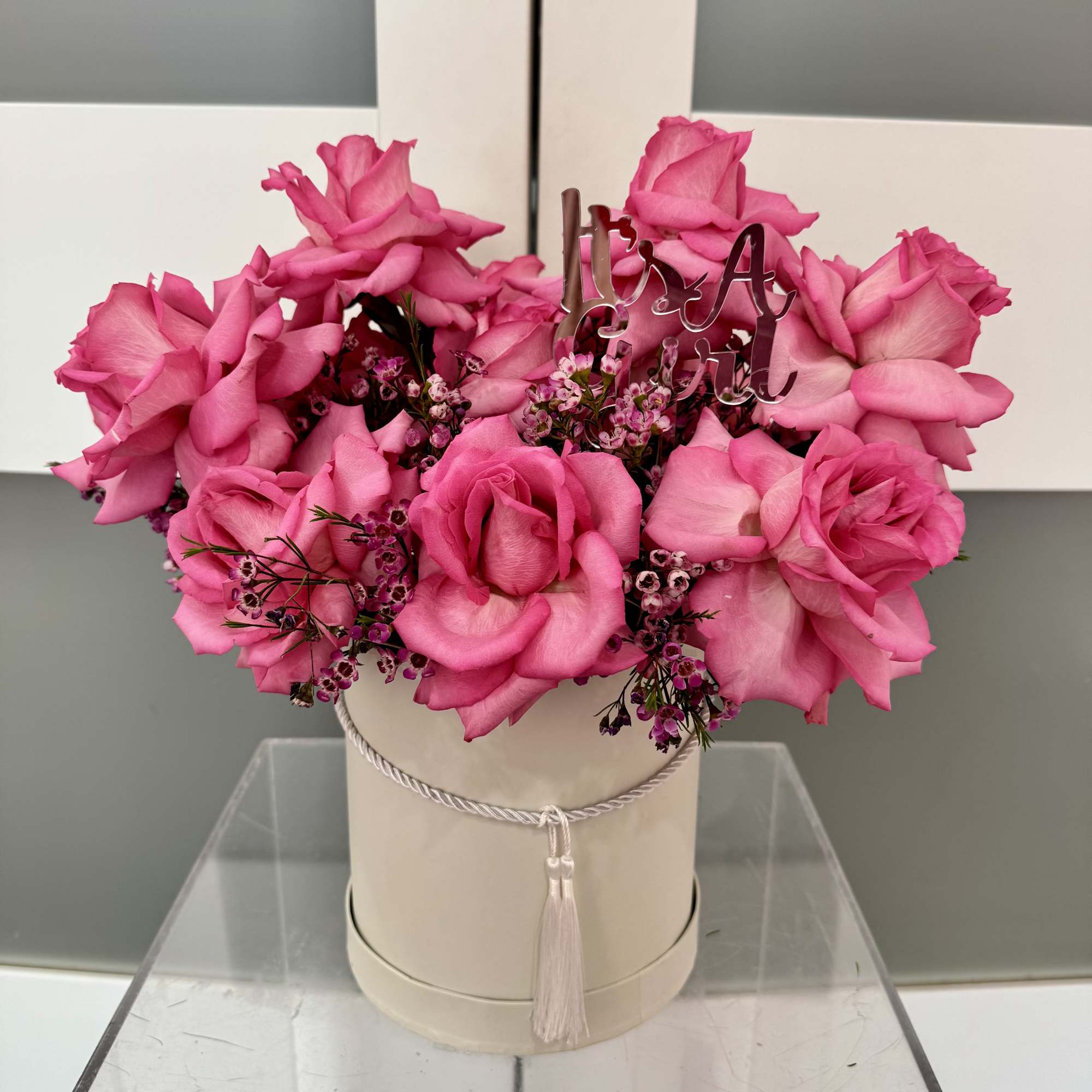 Pink rose arrangement in a round hat box with a tassel tie