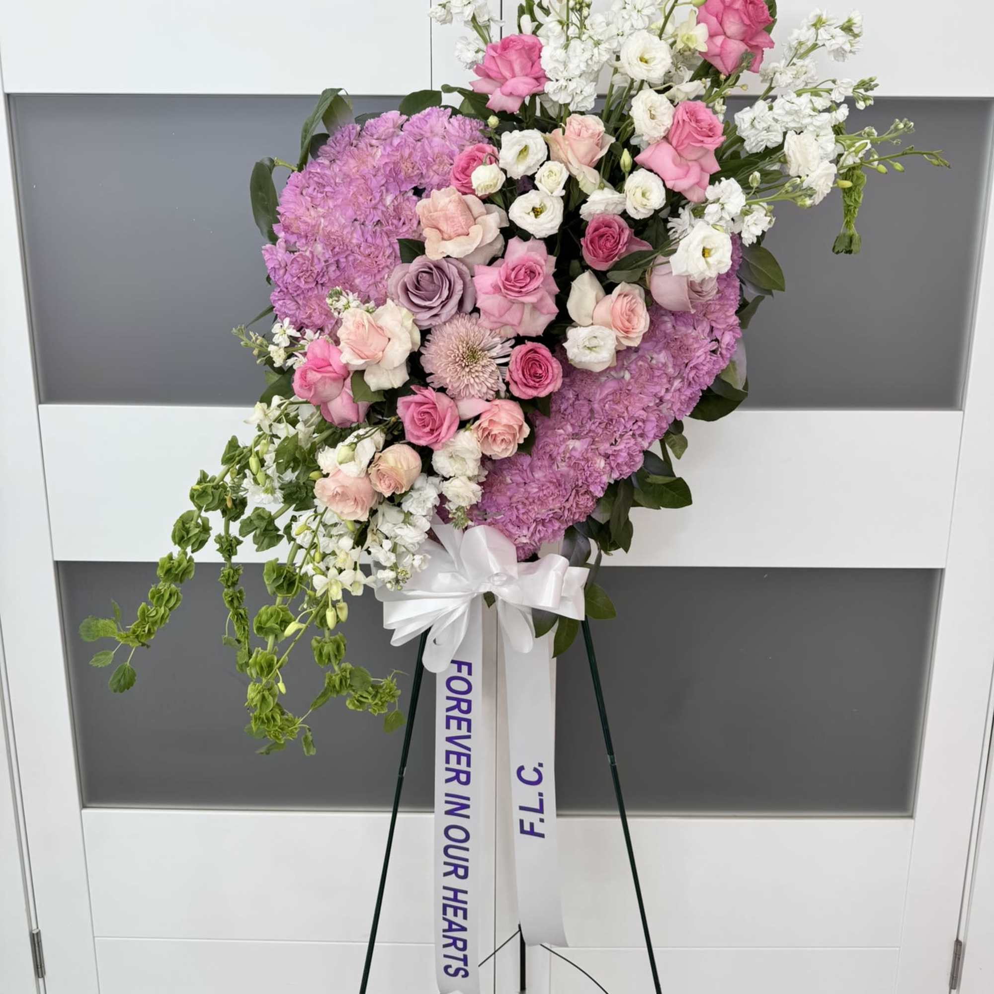 Pink and white floral standing spray on an easel with a ribbon