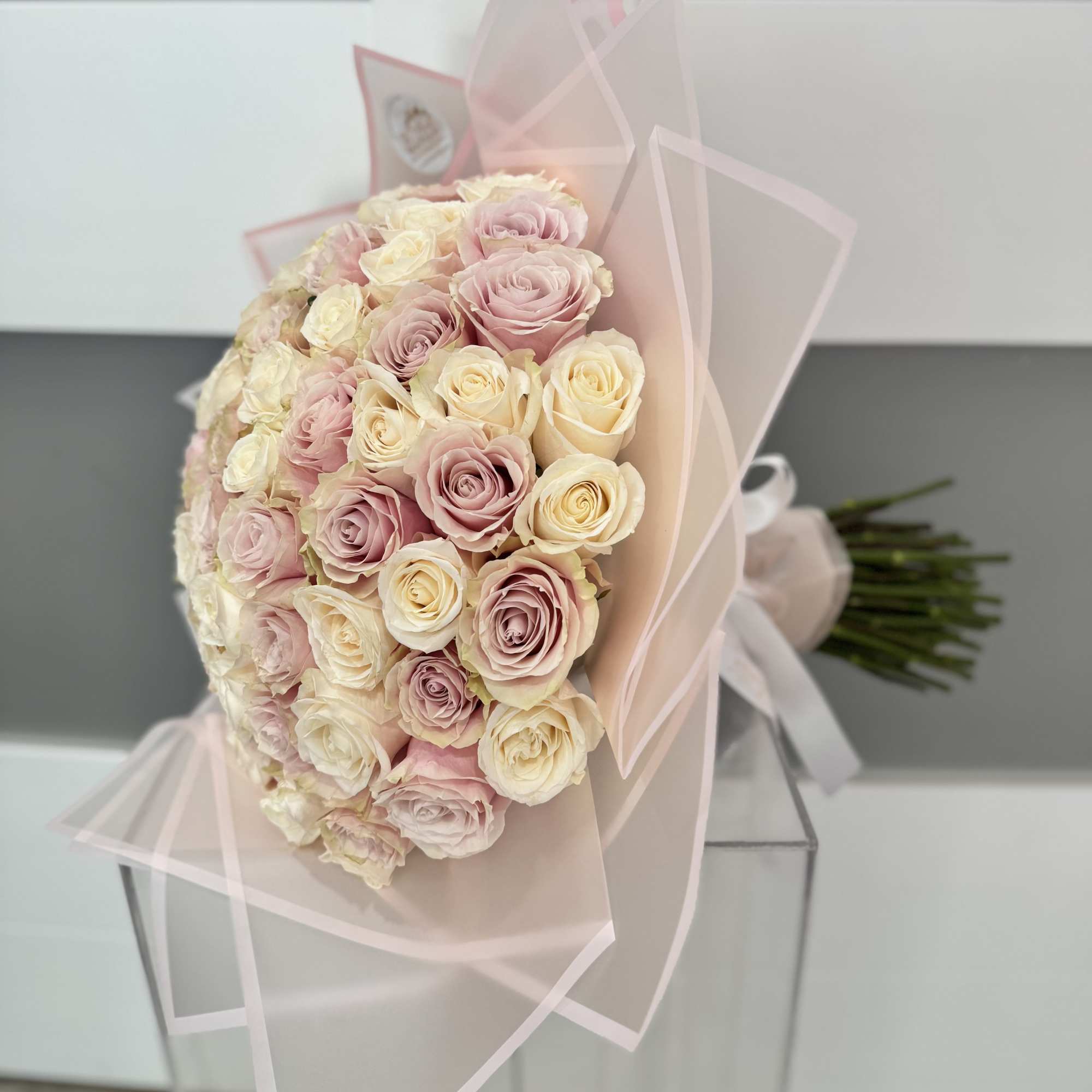 Bouquet of pale pink and cream roses wrapped in translucent pink paper