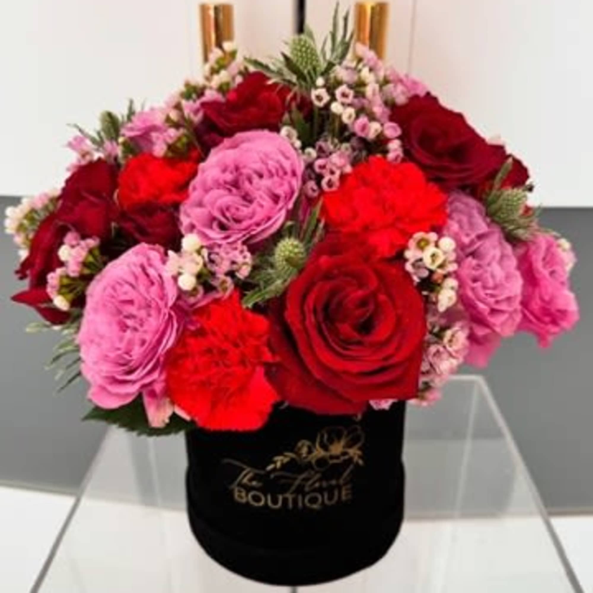 Bouquet of red and pink roses in a black hat box