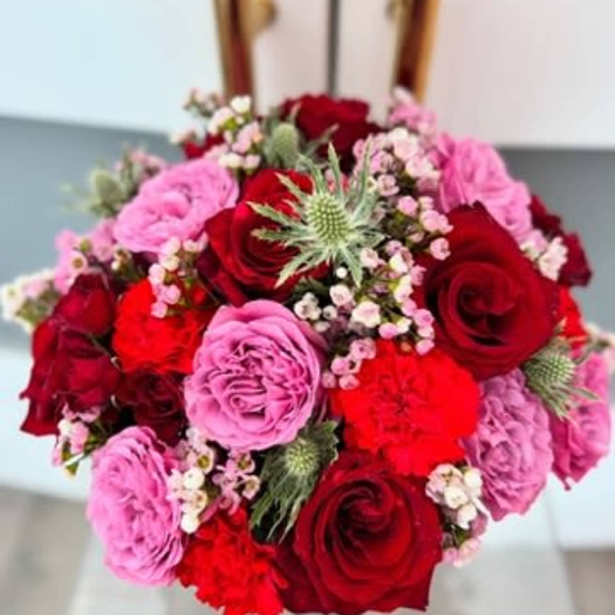 Round bouquet of red and pink roses with small filler flowers