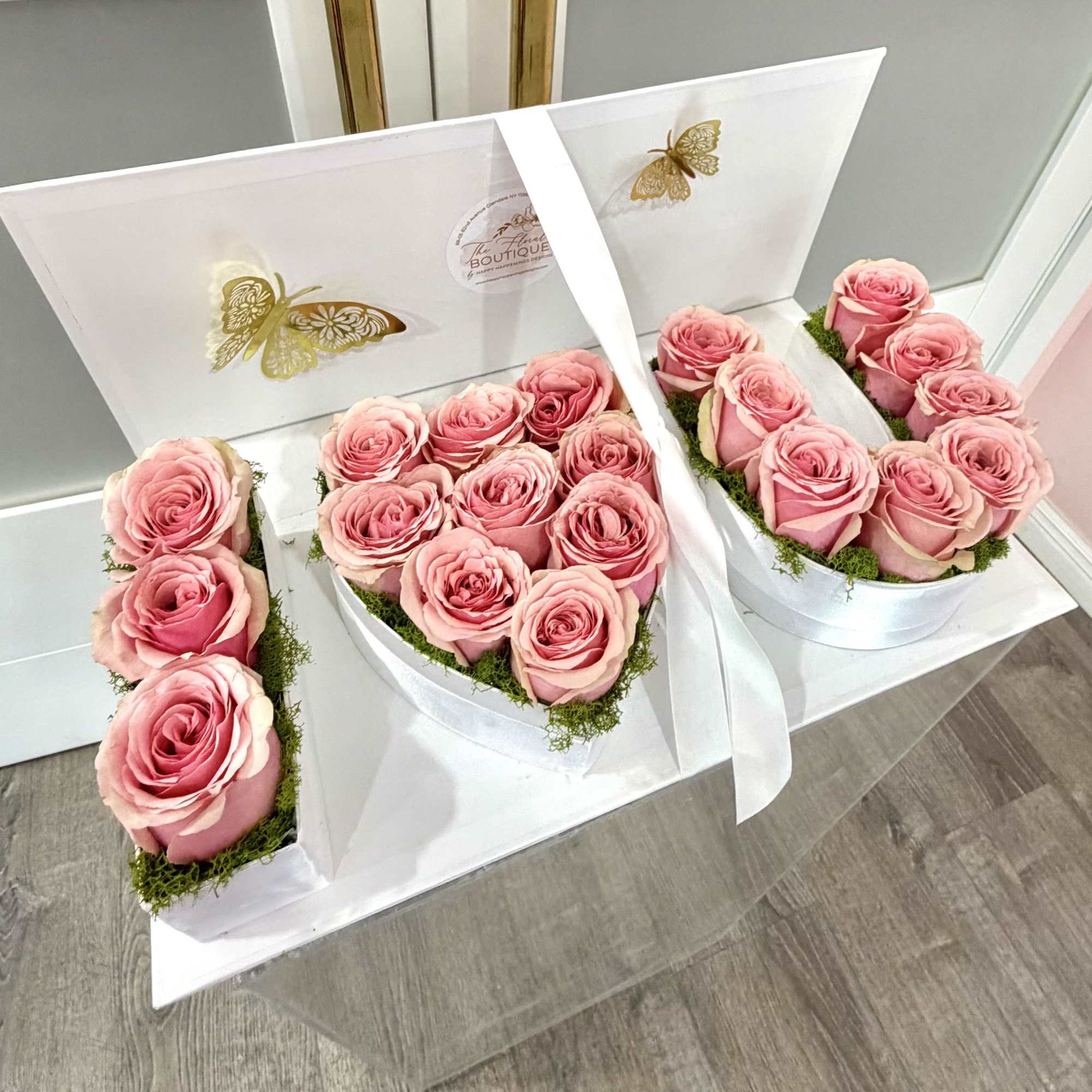 Pink roses arranged in white heart-shaped boxes with a ribbon