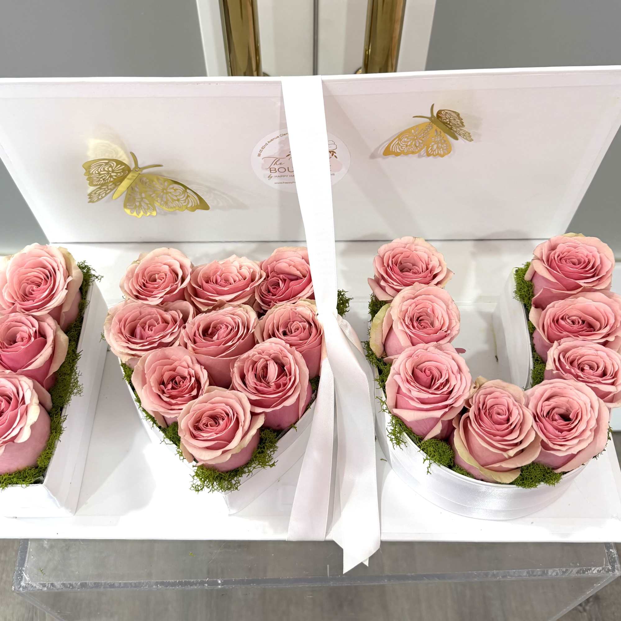 Pink roses arranged in white gift boxes with butterfly decorations