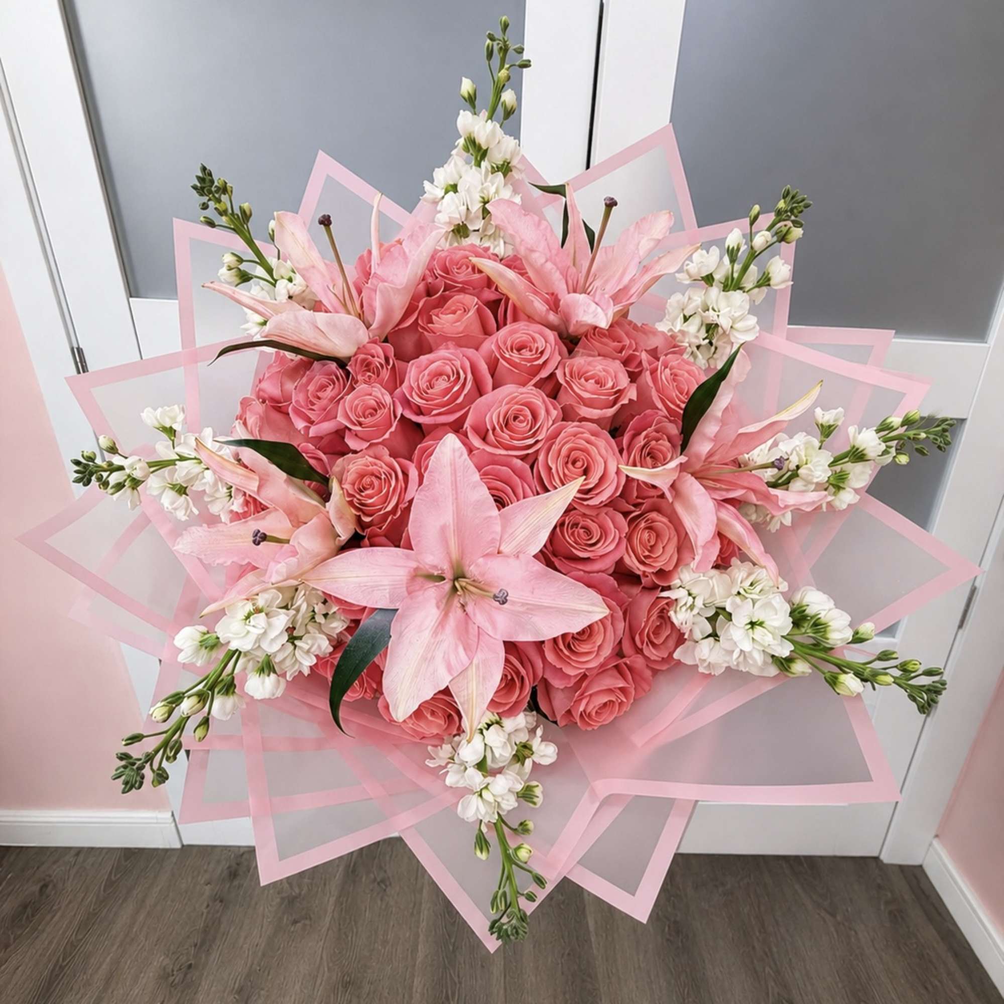 Pink rose bouquet with lilies and white accent flowers wrapped in pink paper