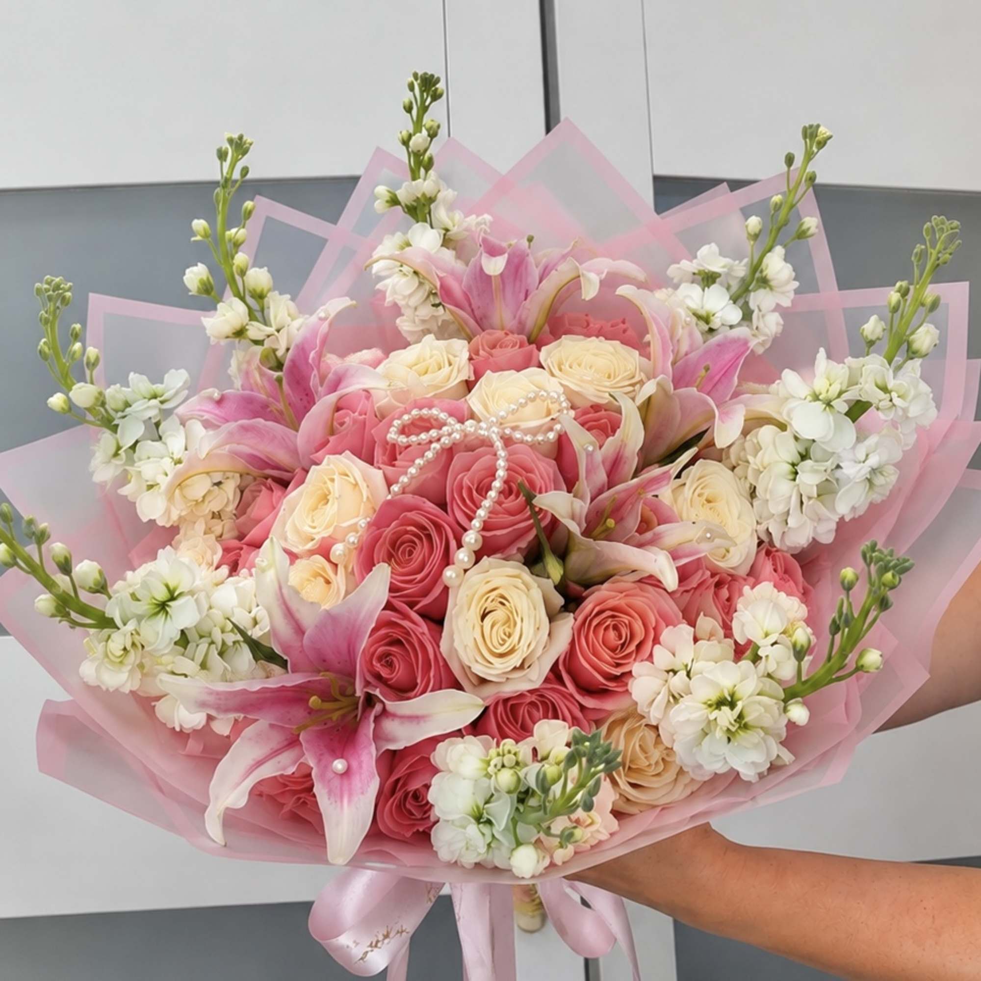 Pink and cream rose bouquet with lilies and white flowers wrapped in pink paper