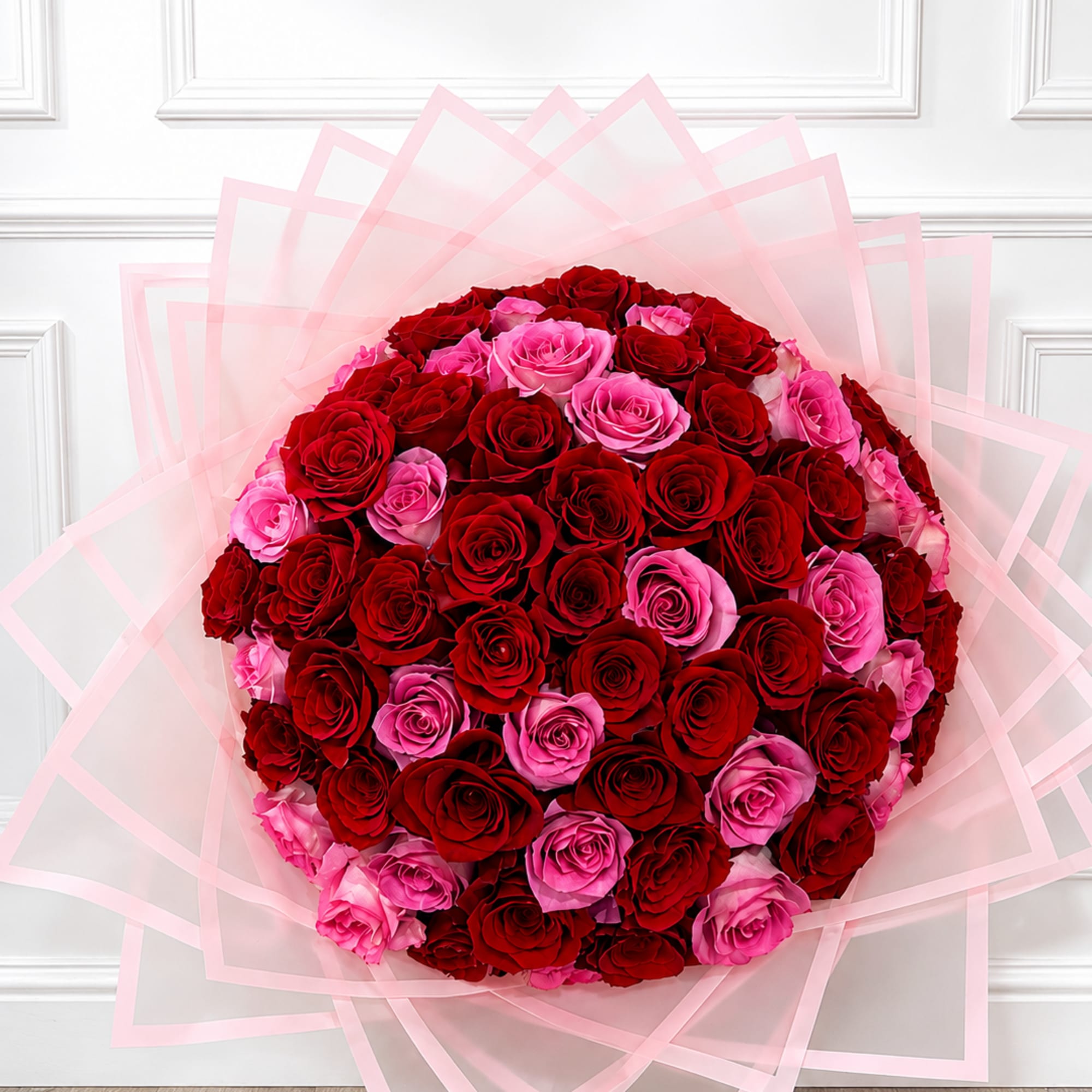 Large bouquet of red and pink roses wrapped in pale pink paper