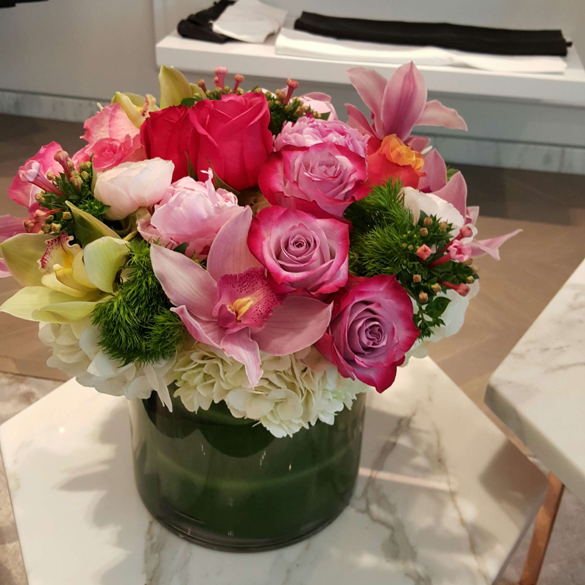Pink and white floral arrangement in a green glass vase