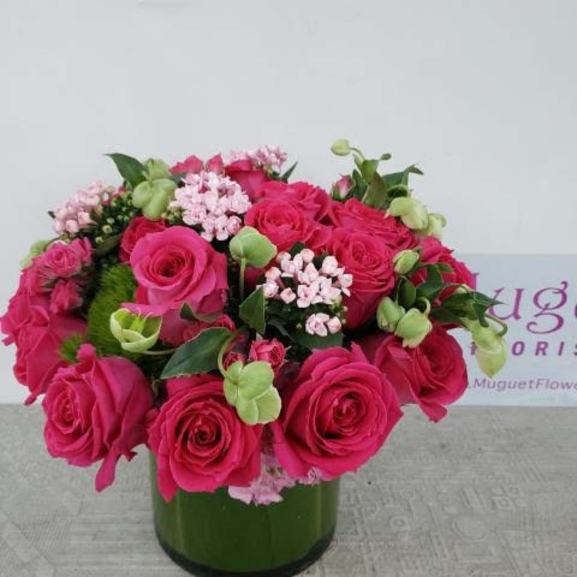 Pink rose bouquet in a green glass vase with small pale pink filler flowers