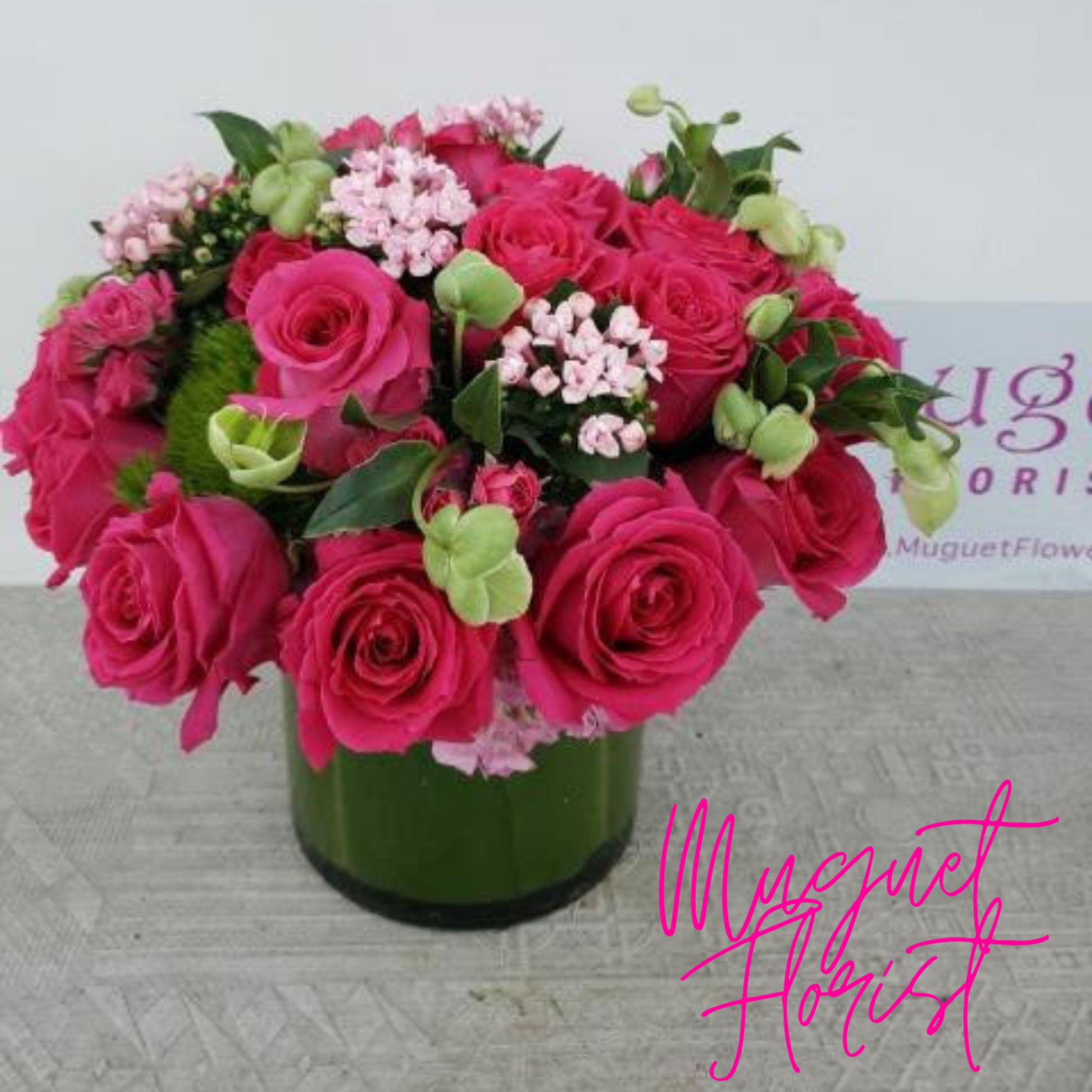 Pink roses and small pale pink flowers arranged in a green glass vase