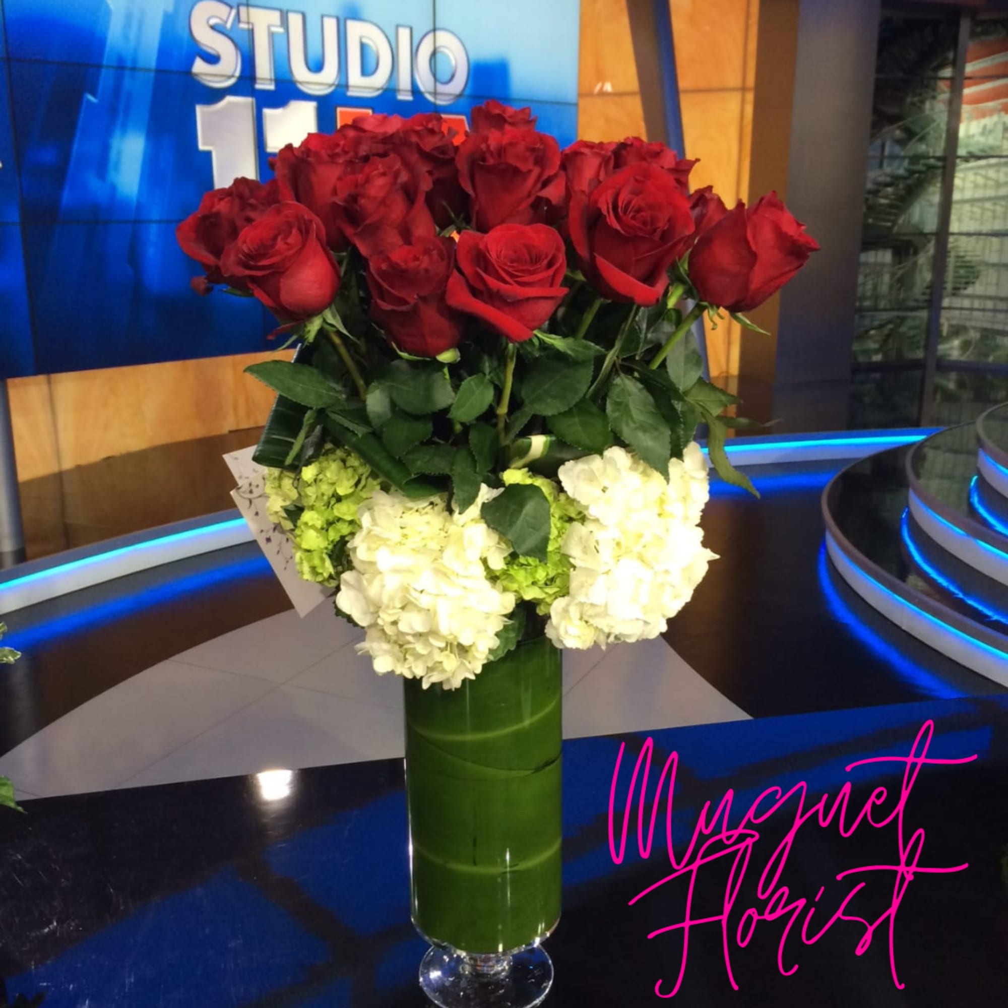 Red roses and white hydrangeas in a tall green vase