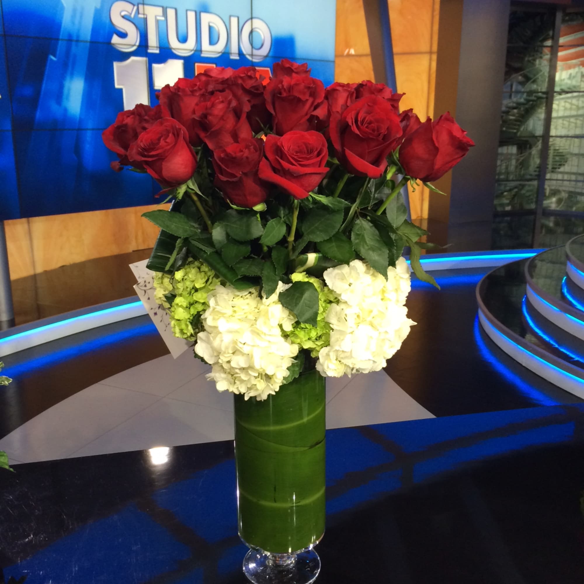 Bouquet of red roses and white hydrangeas in a tall green vase