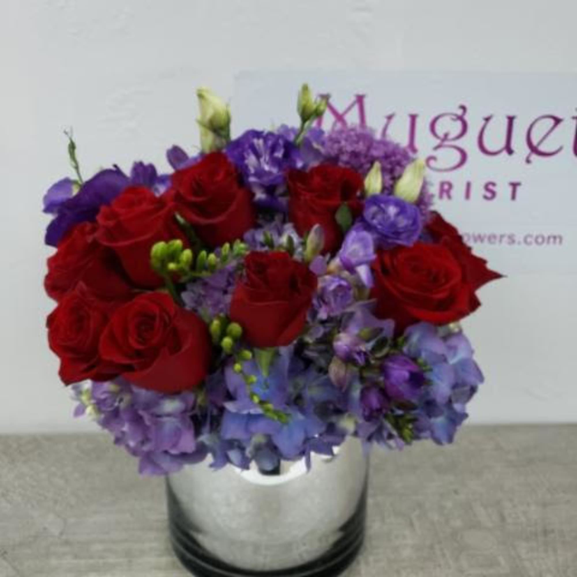 Red roses and purple flowers arranged in a silver vase, photo 3 of 3