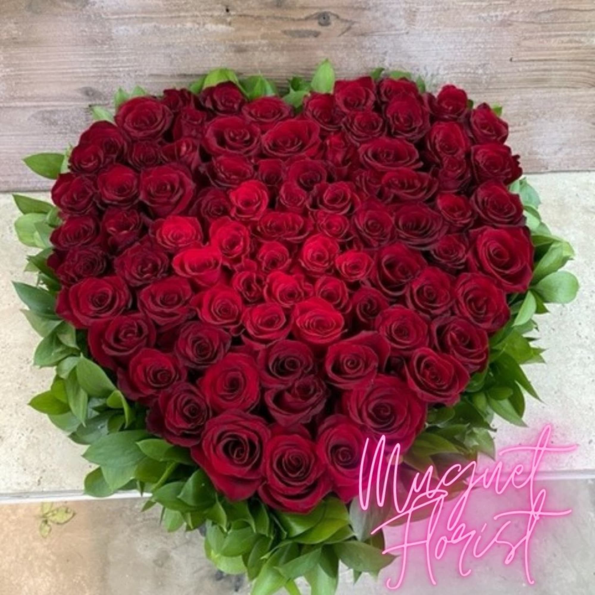 Heart-shaped bouquet of red roses with green foliage