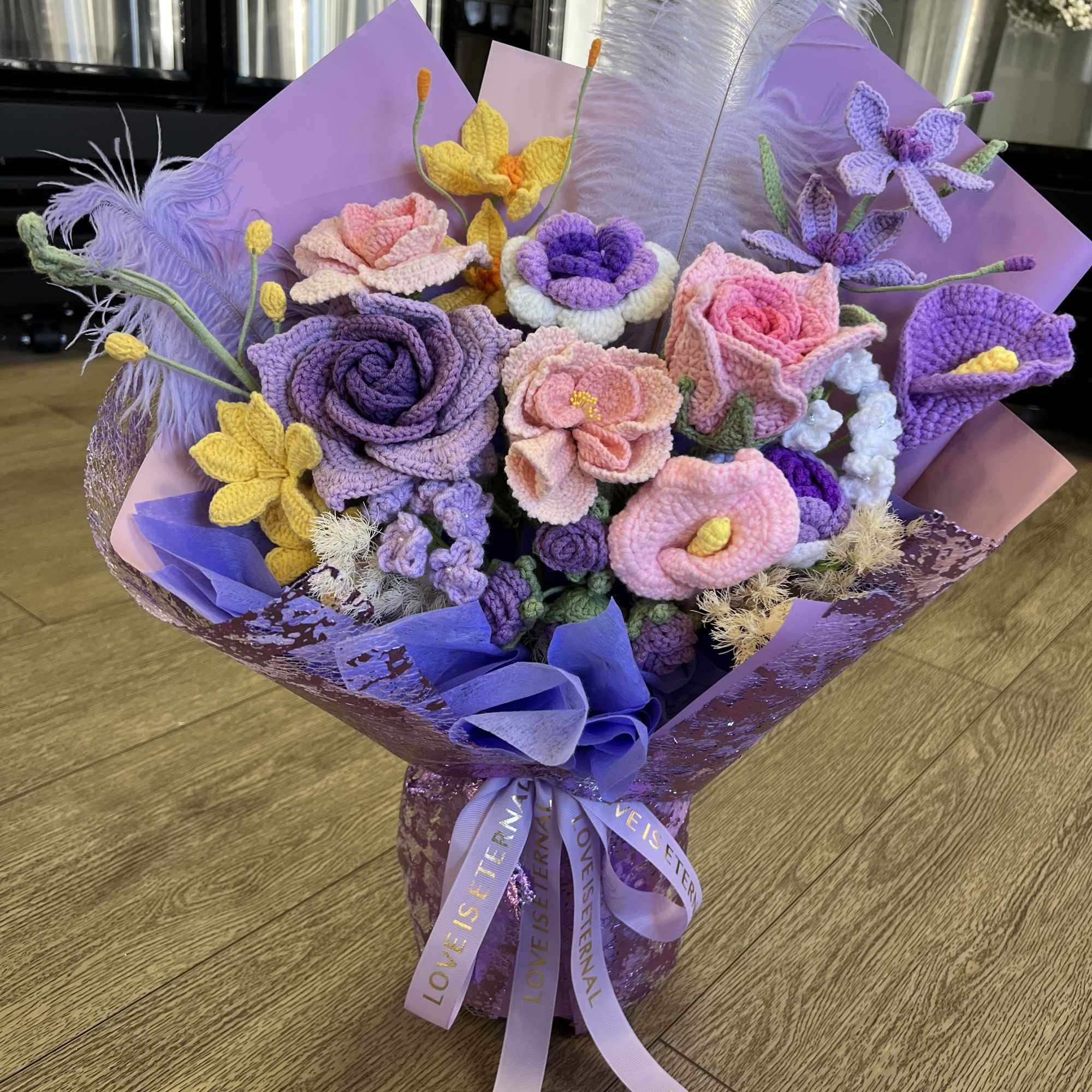 Bouquet of crocheted purple, pink, and yellow flowers wrapped in lavender paper