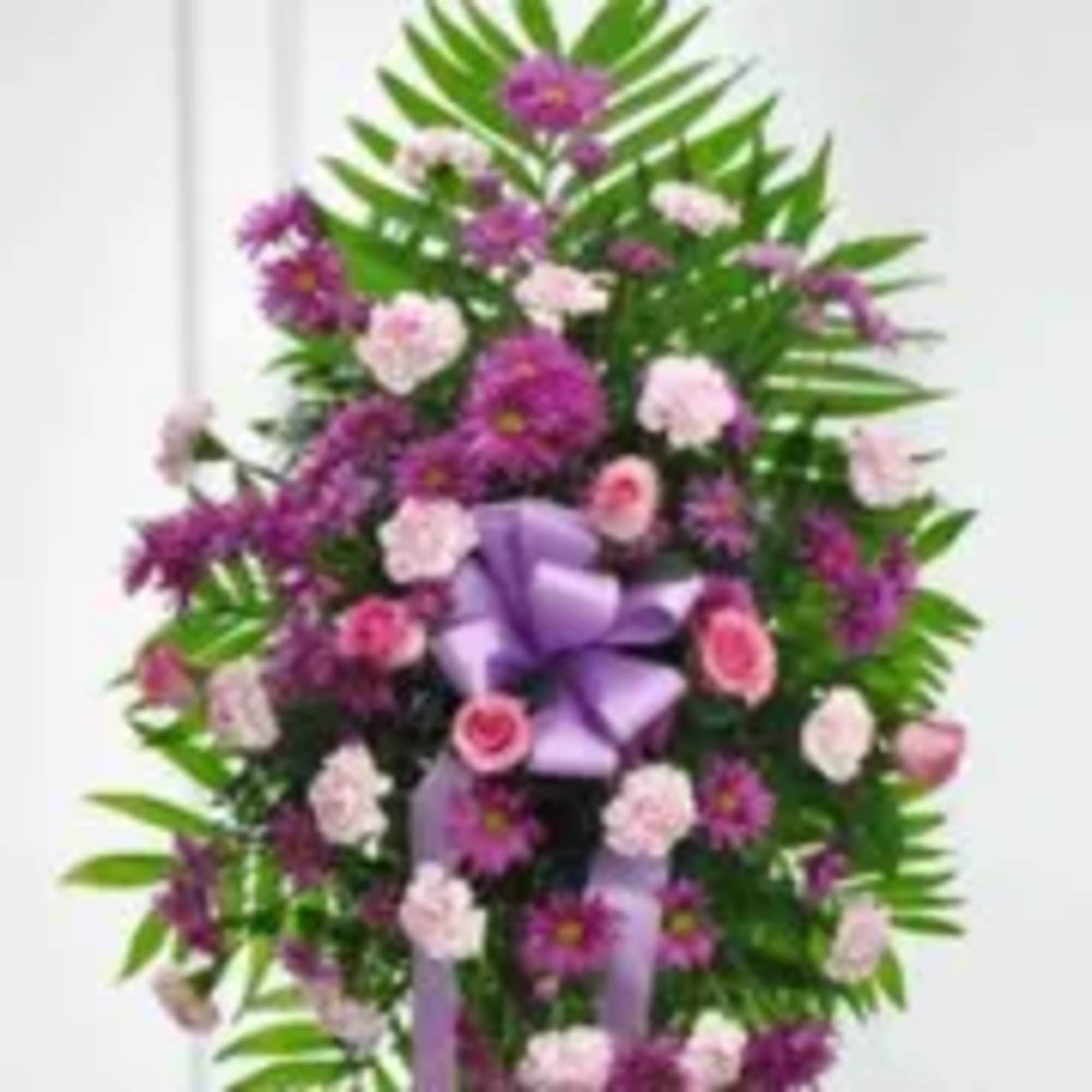 Standing floral spray with purple and pink flowers and a lavender bow