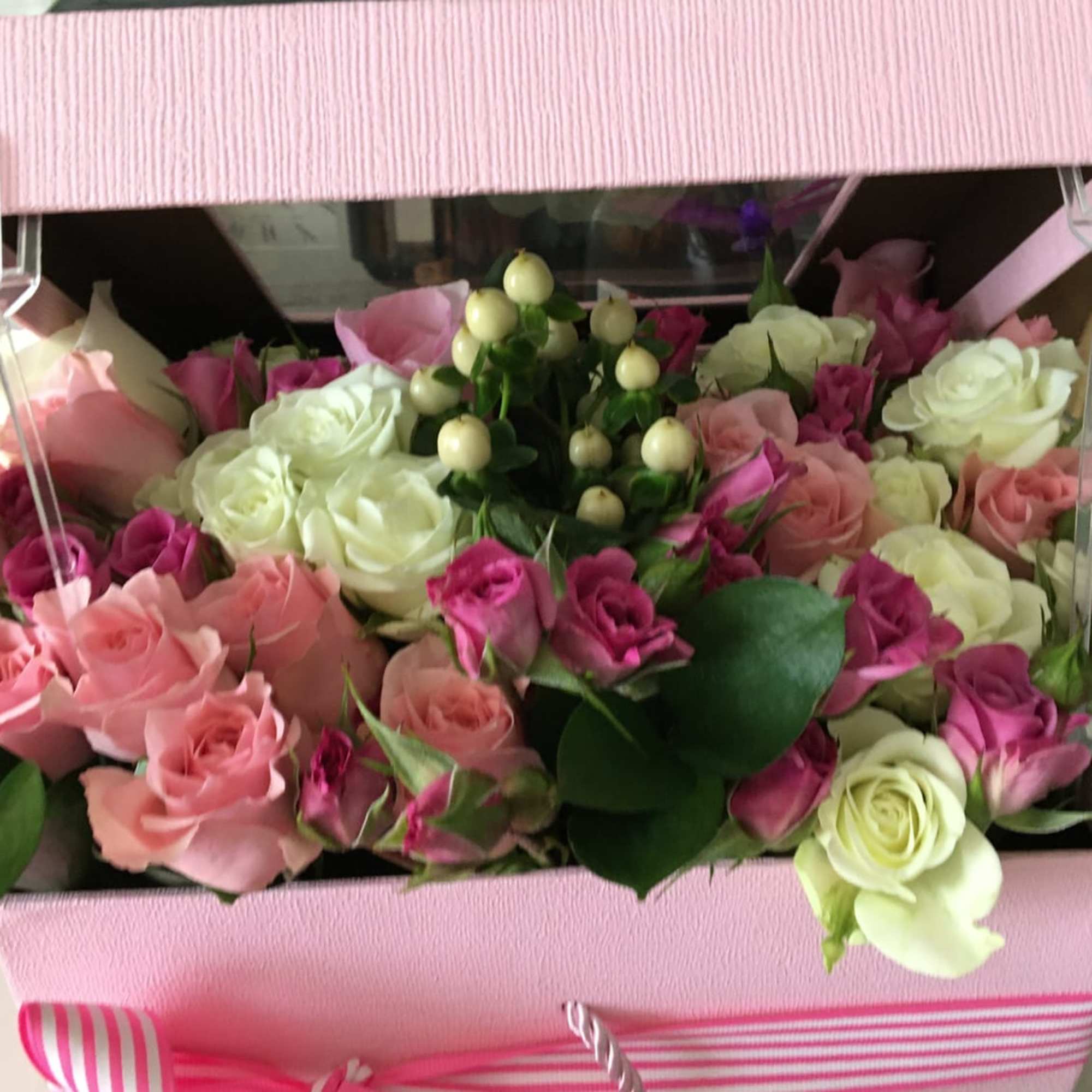 Pink and white roses arranged in a gift box with berries