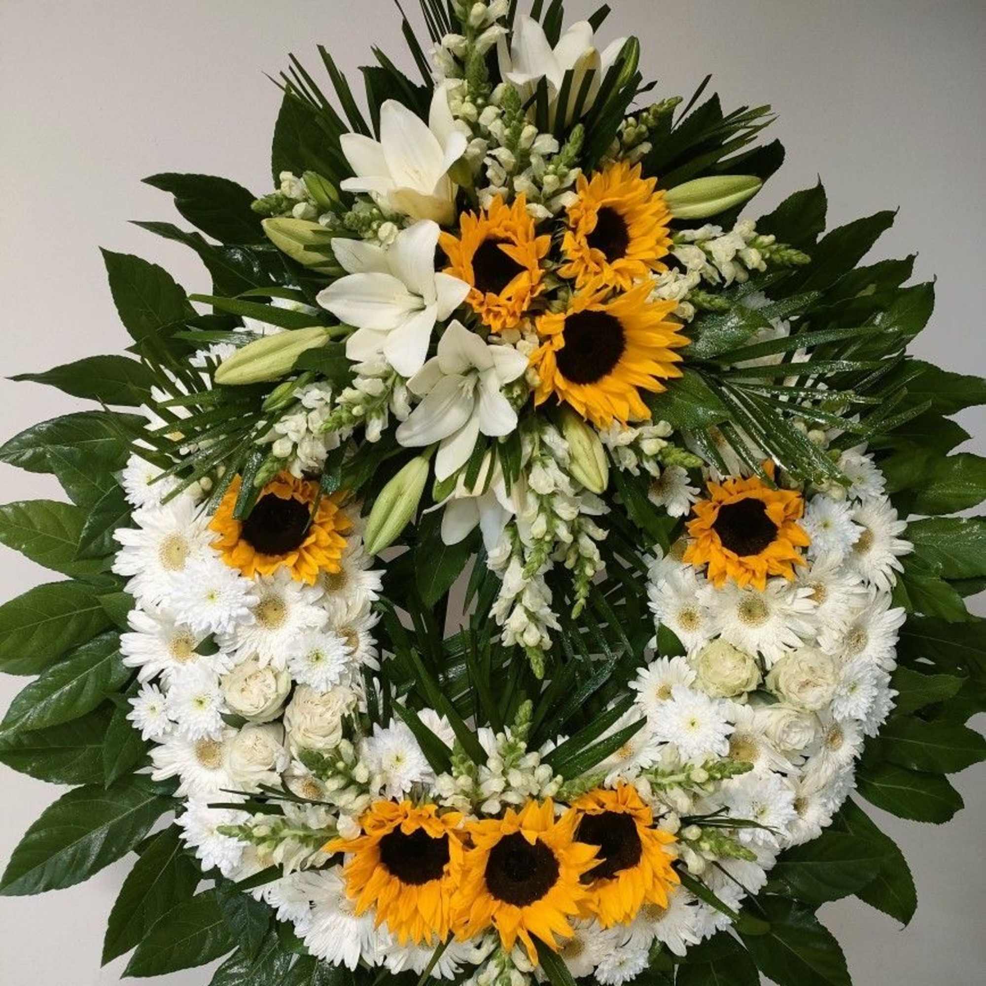 Circular floral wreath with white flowers and yellow sunflowers
