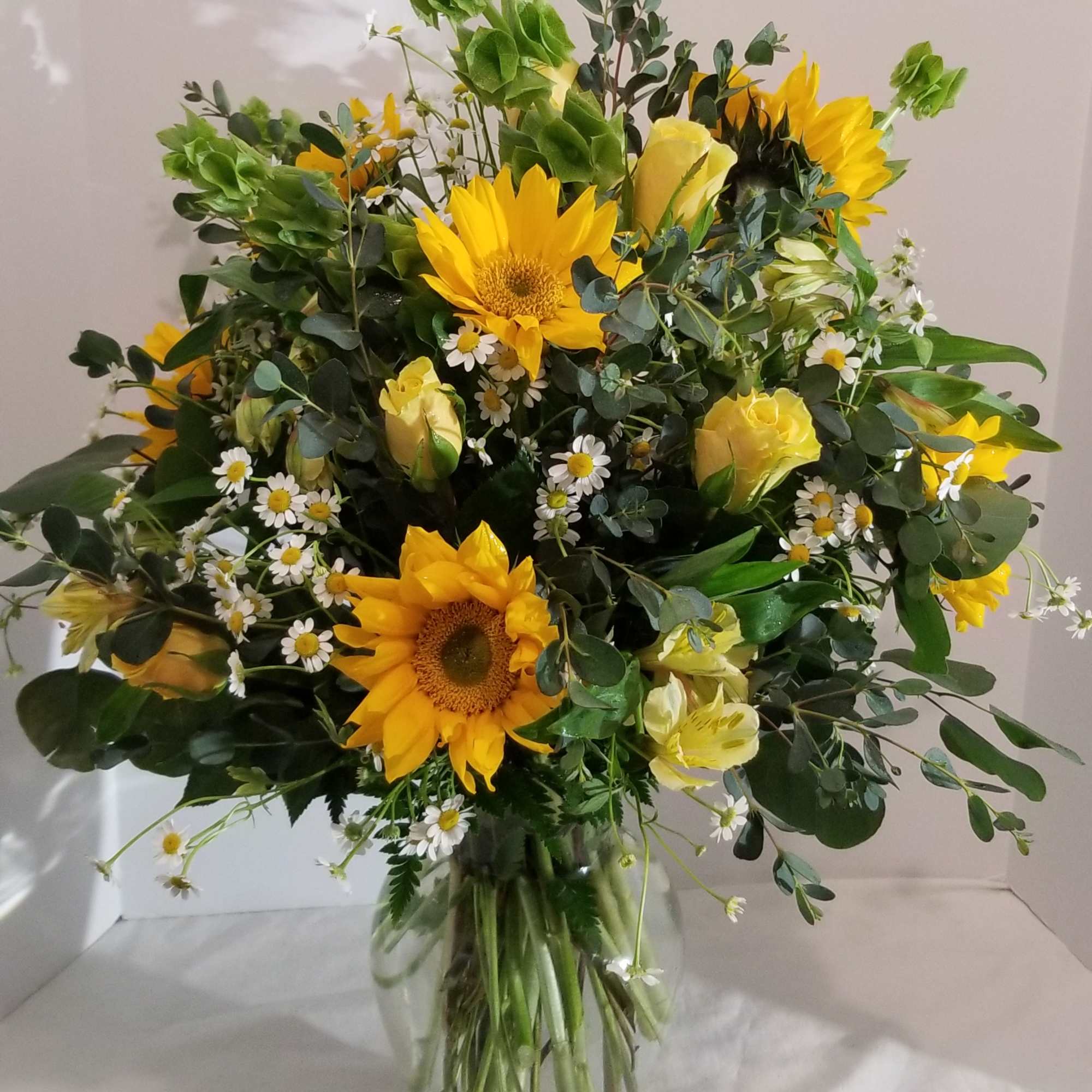 Bouquet of yellow sunflowers and white daisies in a clear glass vase