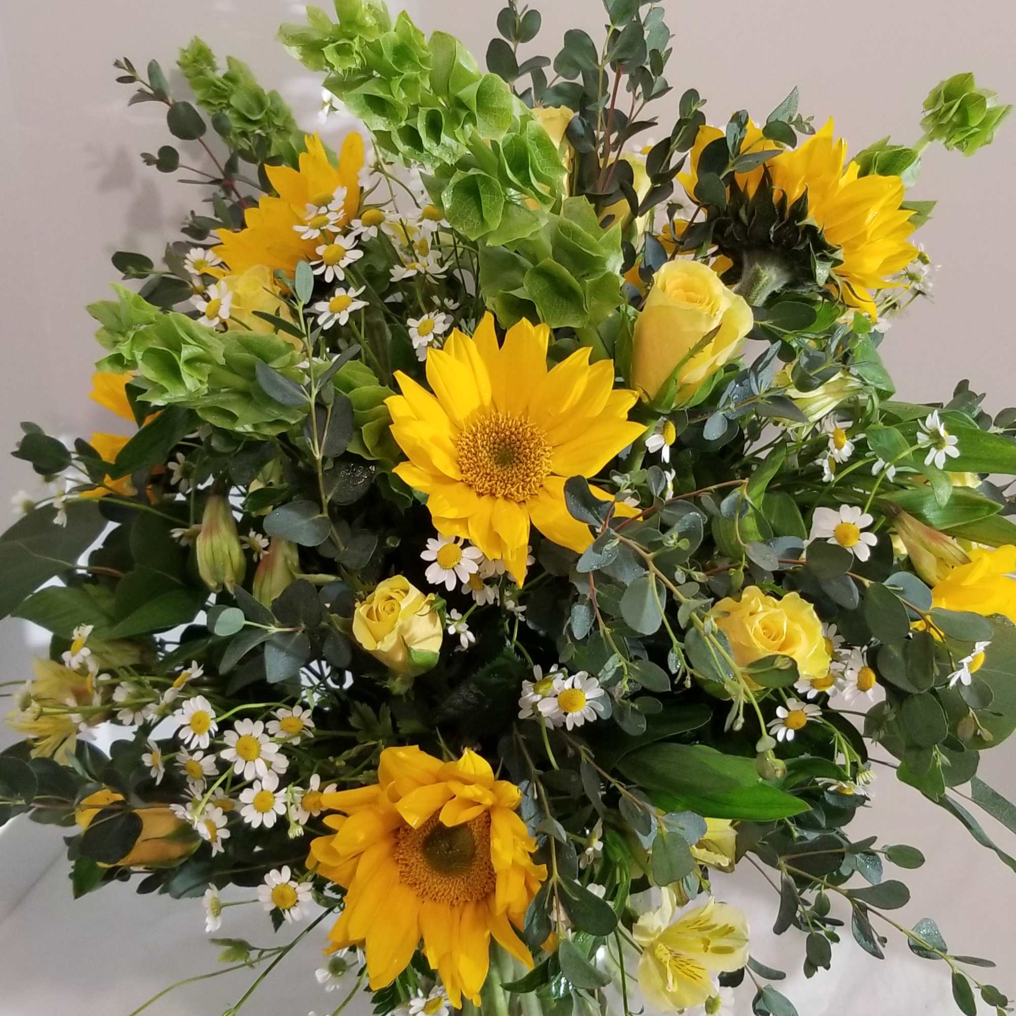 Bouquet of yellow sunflowers and roses in a glass vase