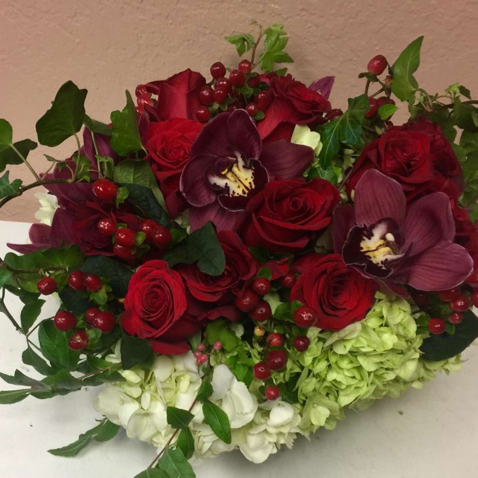 Bouquet of red roses, purple orchids, and green hydrangeas with berries