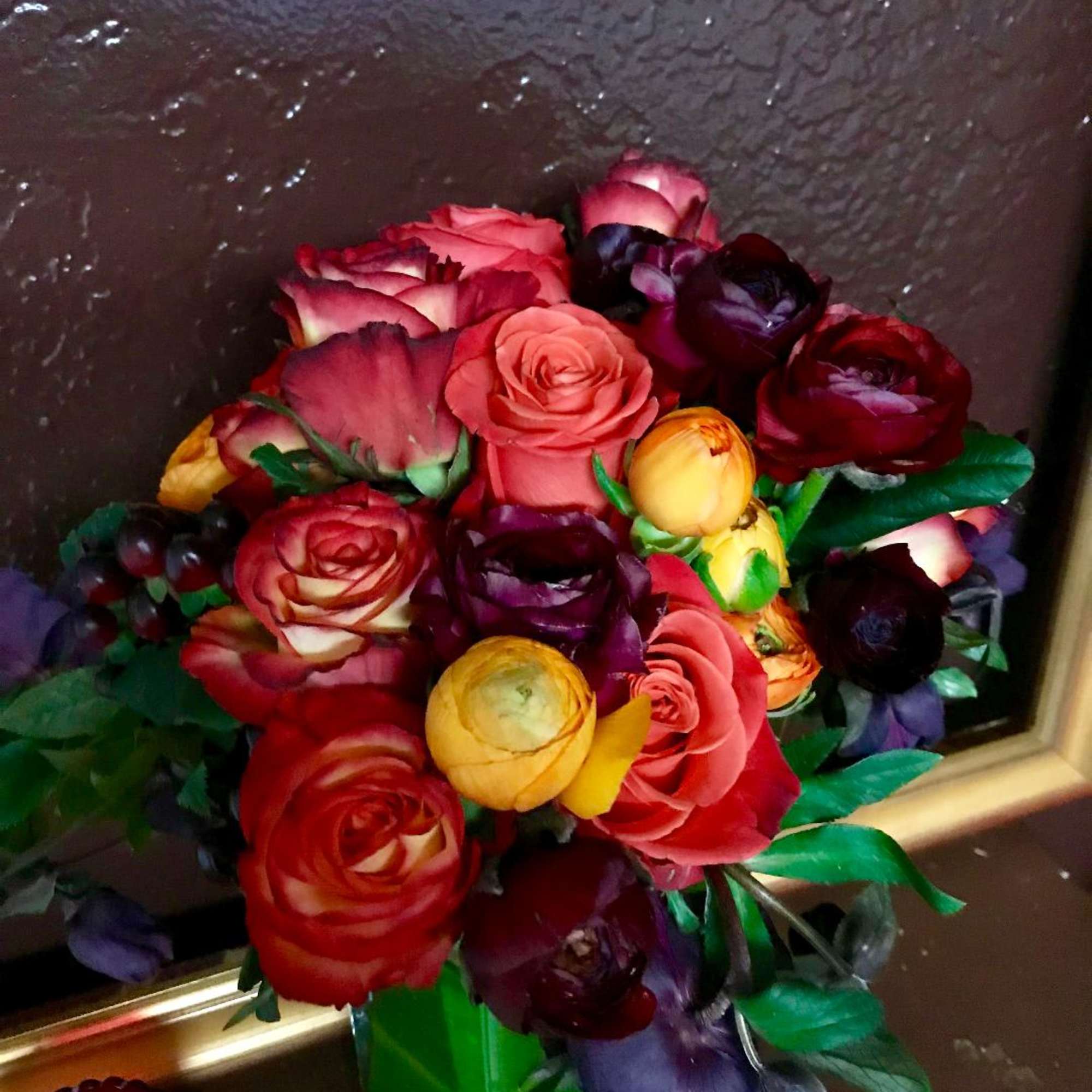 Bouquet of multicolored roses and ranunculus in a green vase