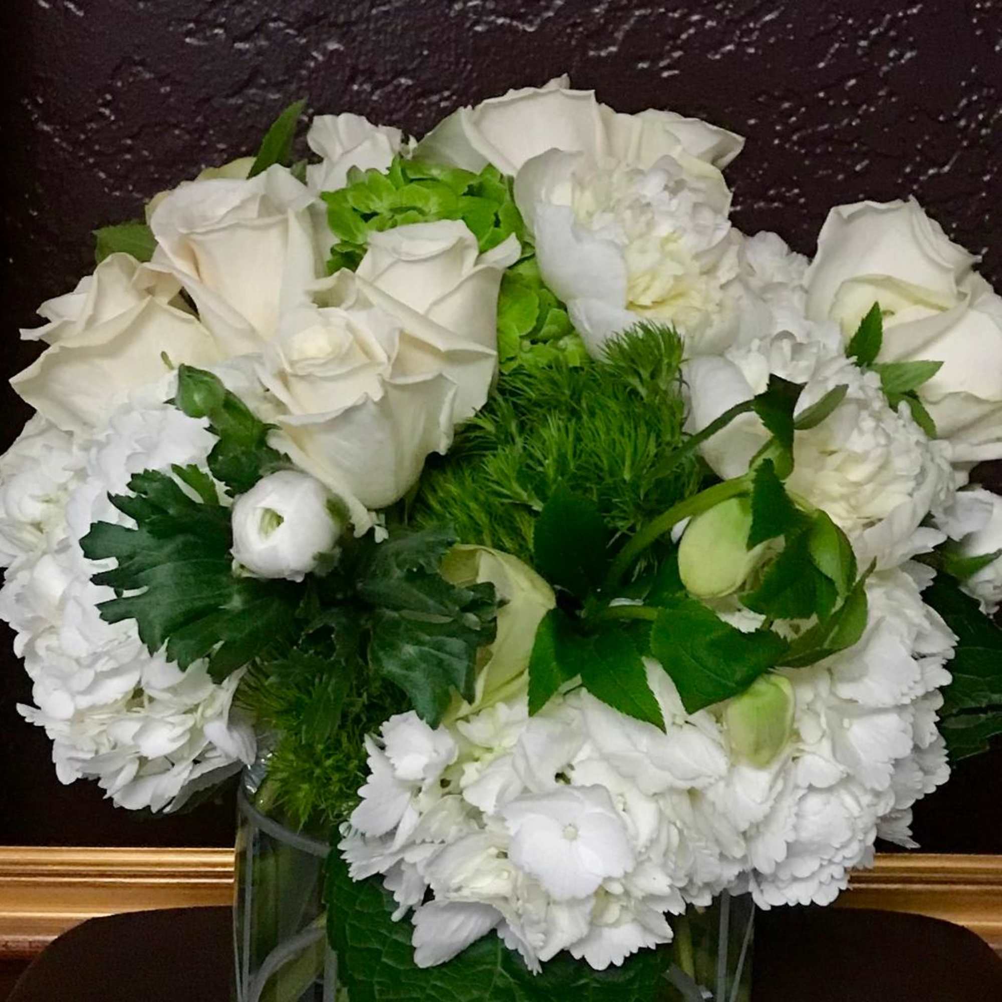 White roses and white blooms arranged in a glass vase