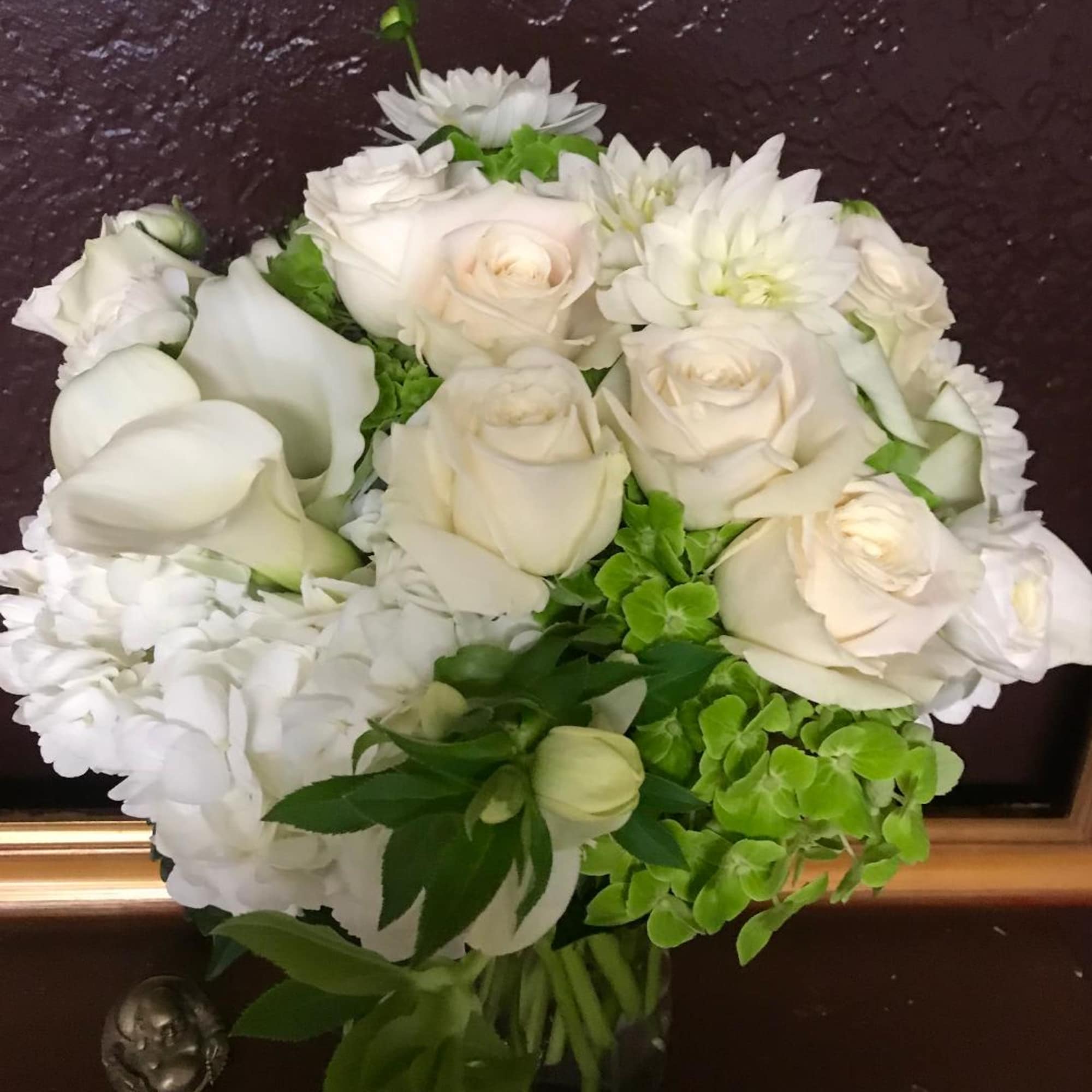 White roses, calla lilies, and hydrangeas in a bouquet with green accents