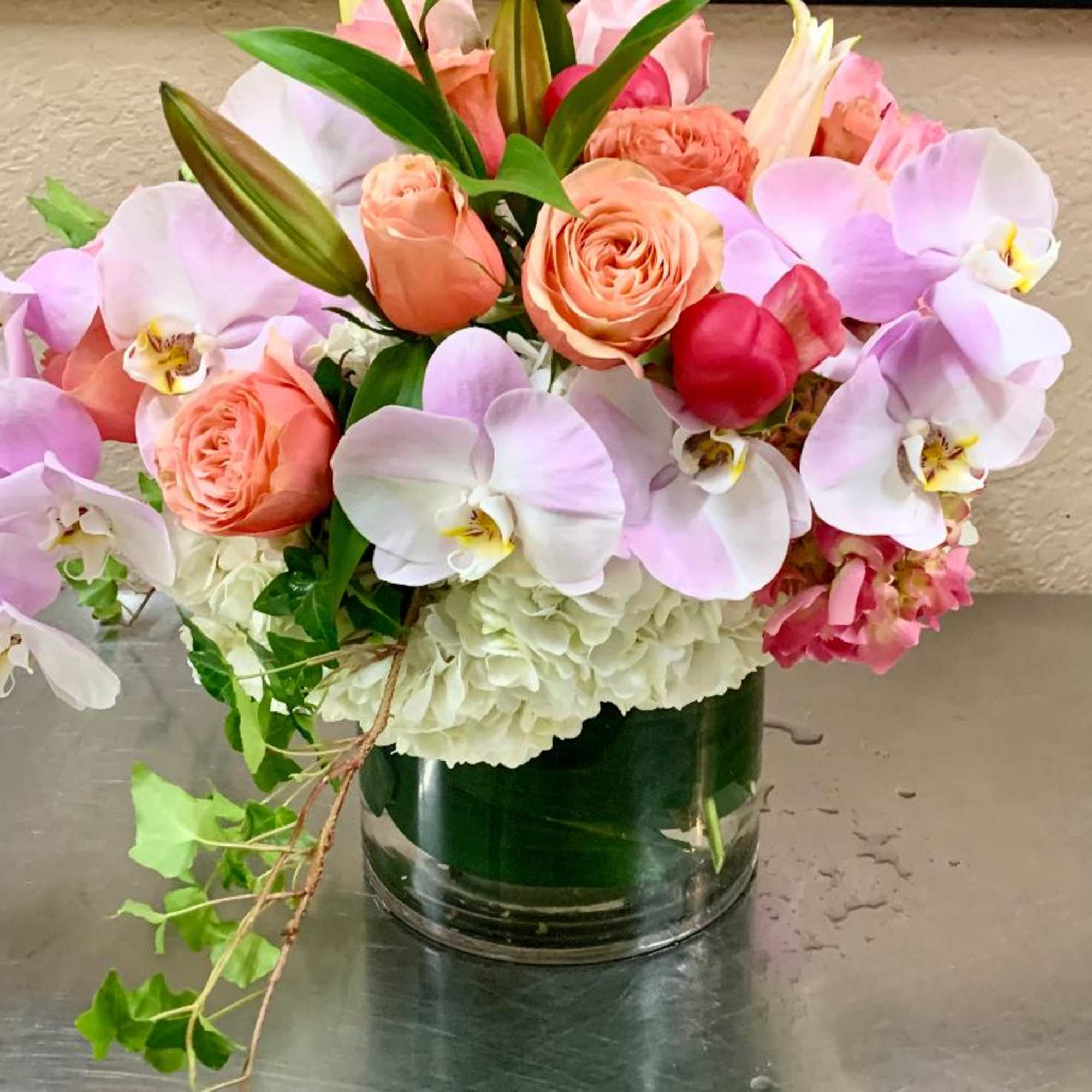 Pink orchids and peach roses arranged in a glass vase