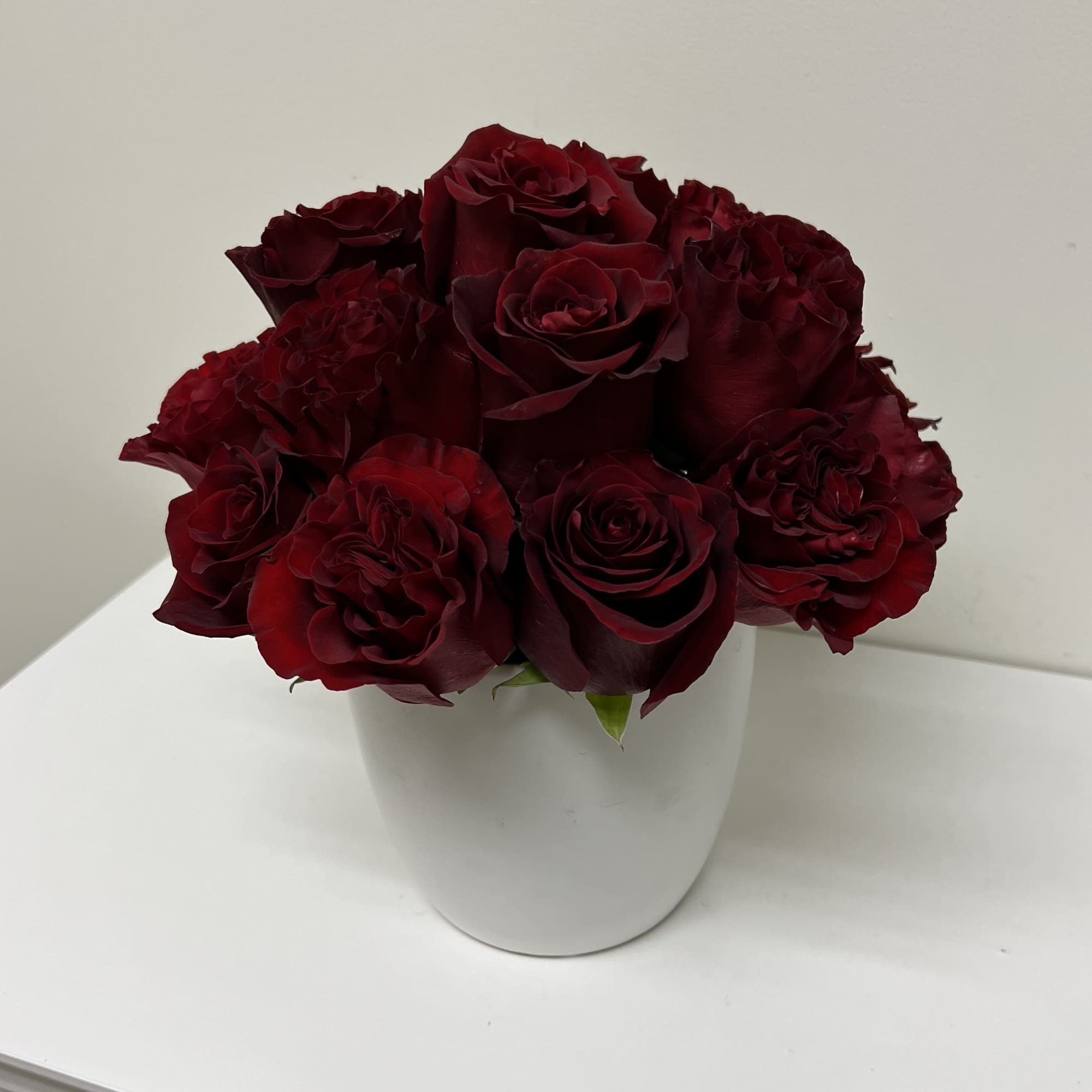 Deep red roses arranged in a white vase
